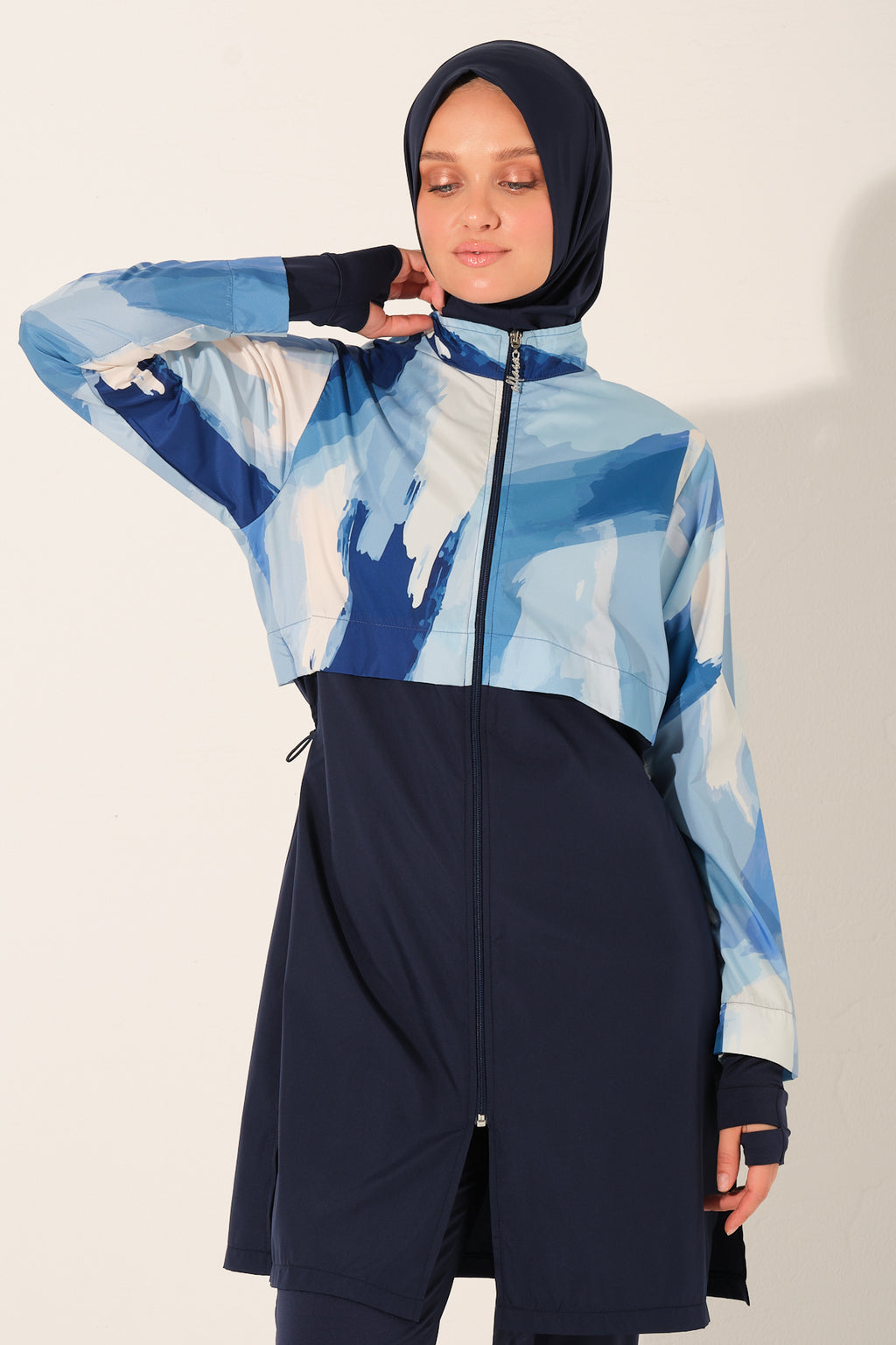 Person wearing a blue and navy patterned burkini with a hijab on a plain background