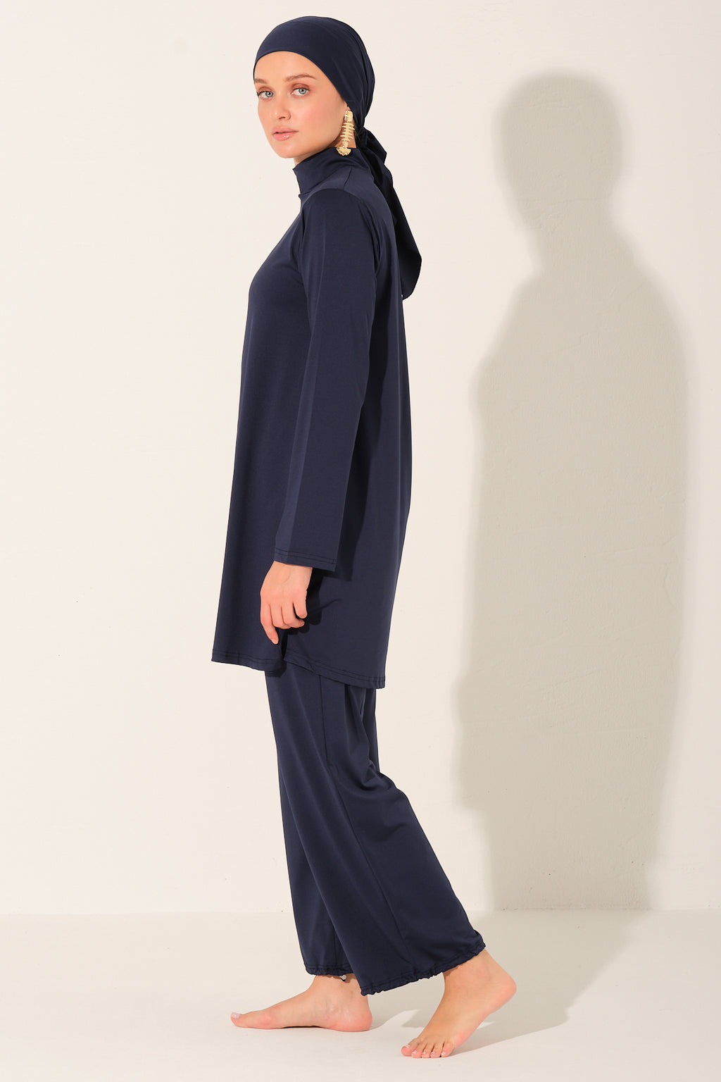 Person wearing a navy blue outfit with a matching headscarf on a white background