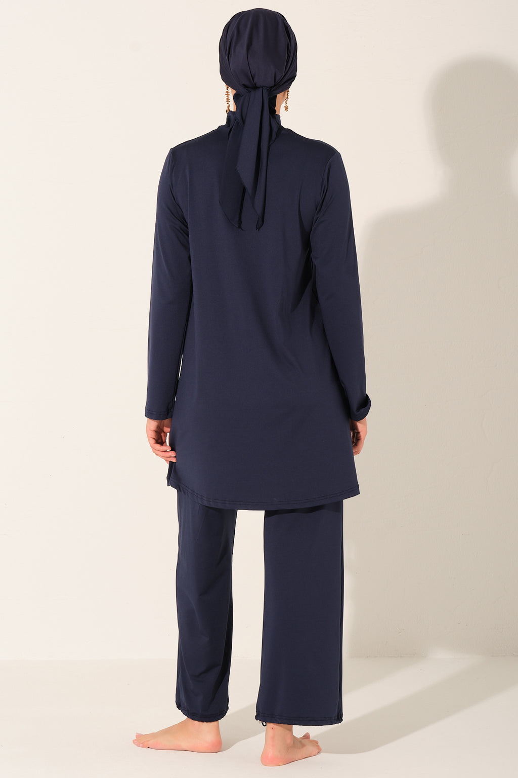 Person wearing a navy blue outfit with a matching headscarf on a white background