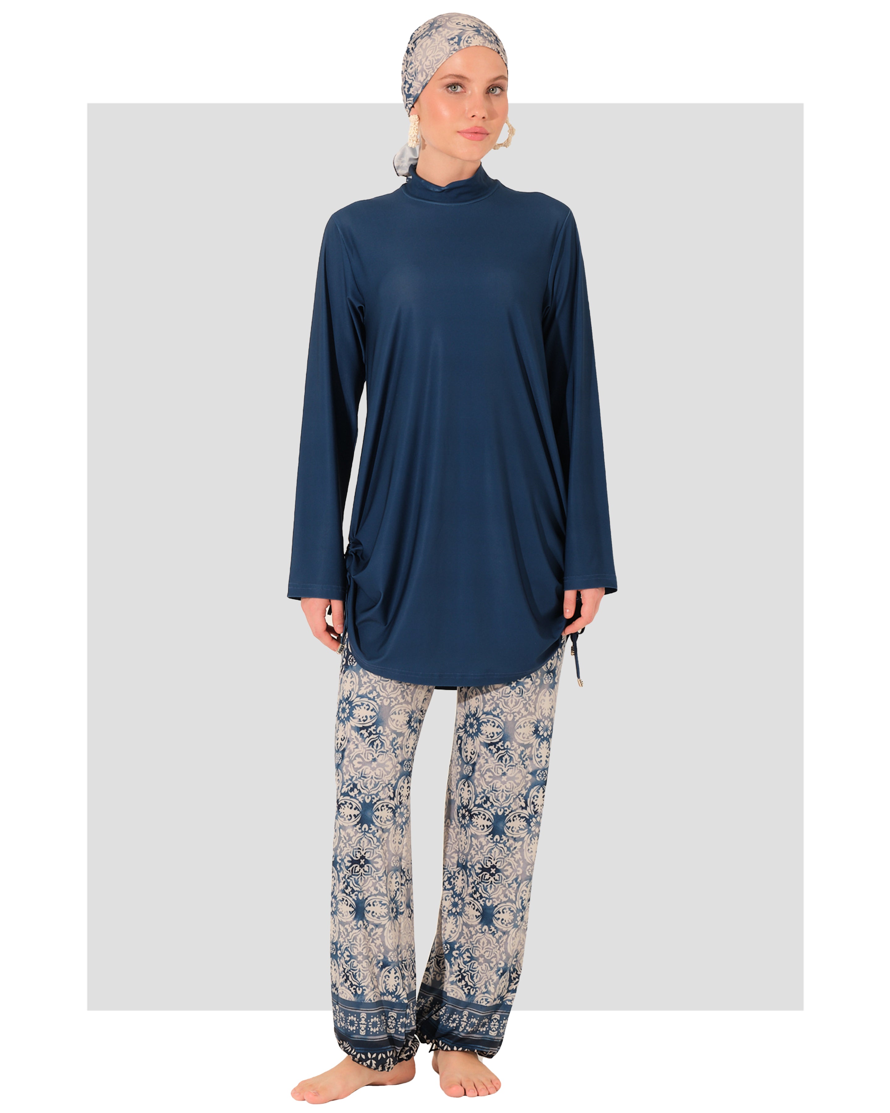Woman wearing a navy long-sleeve top and patterned pants on a white background