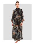 A model wearing a long-sleeve black tunic with a high neckline, wide-leg pants with a jungle-inspired print, a sheer printed kimono, and a leopard-print headscarf.