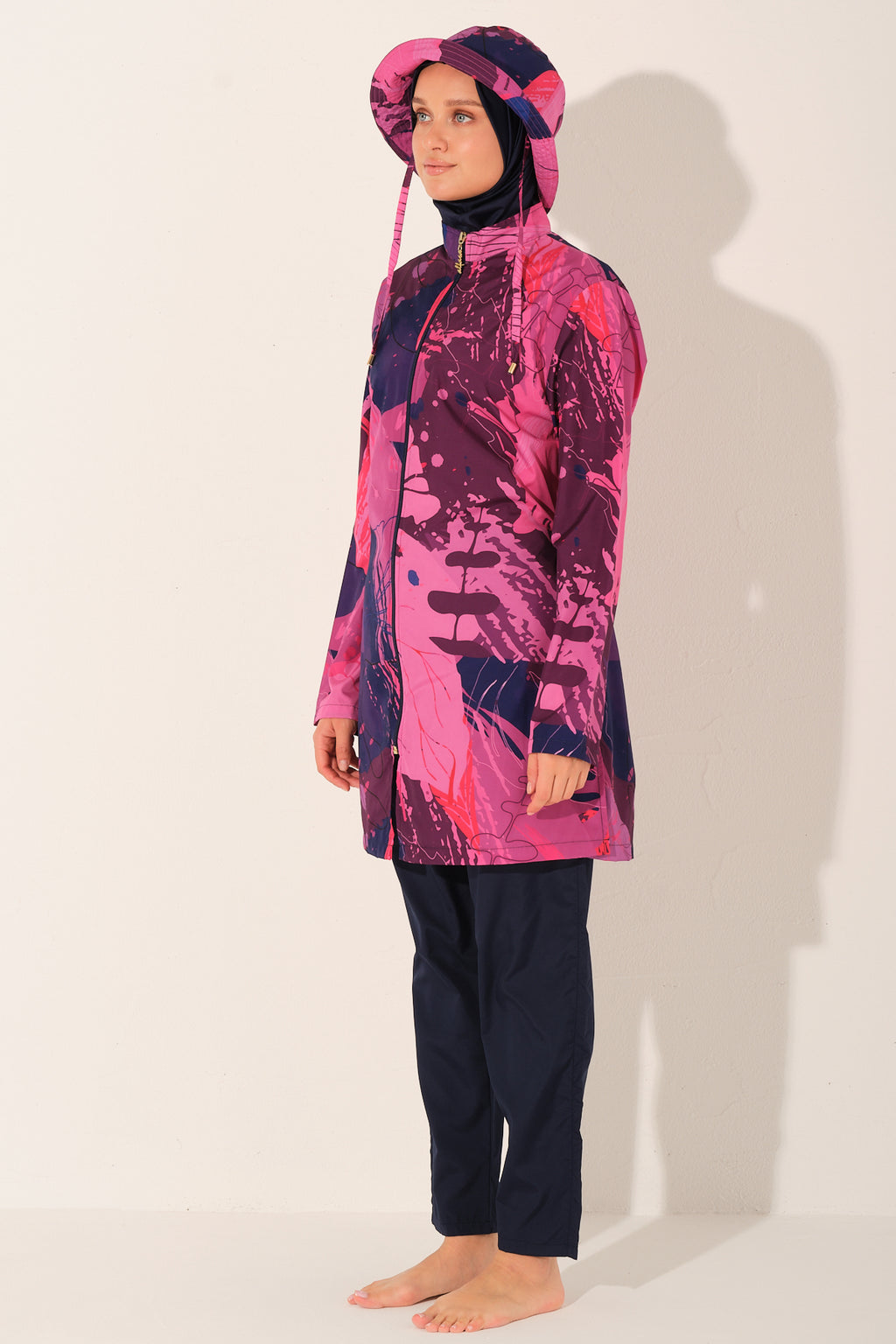 Model wearing pink Abstract print burkini set, side view, on light background.