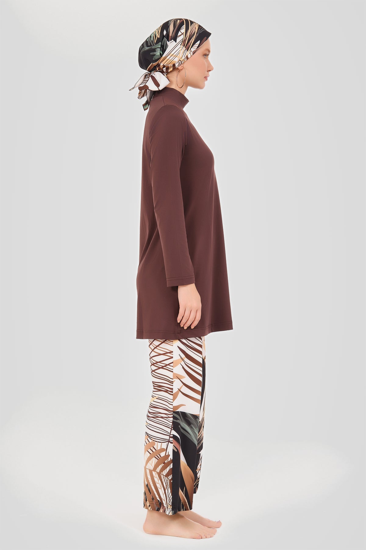Model in rich brown modest swimwear set side profile with patterned head covering.