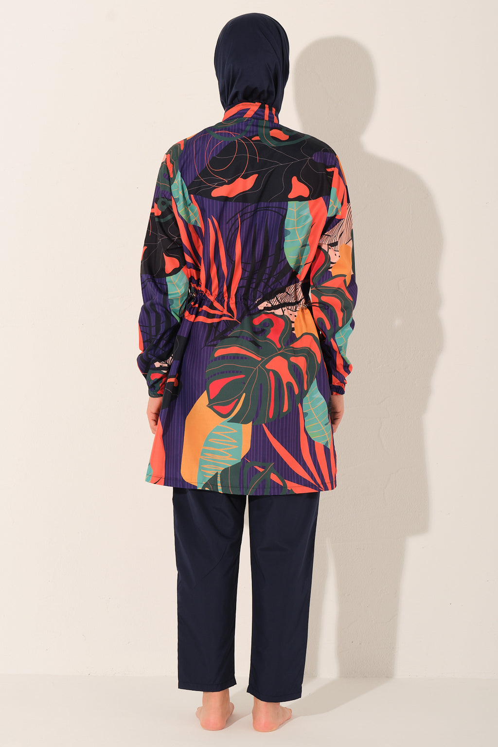 Model wearing navy tropical print burkini set, back view, showing waist detail.