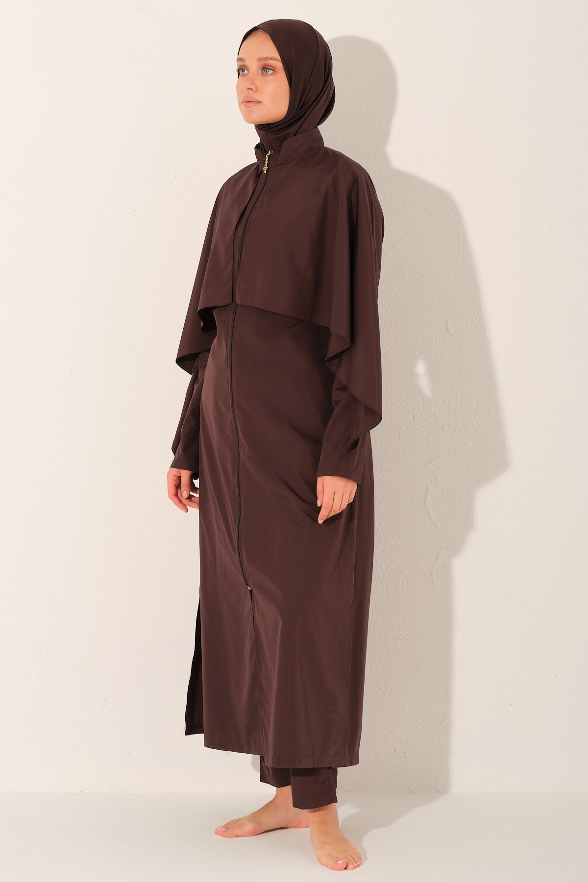 Woman wearing a brown burkini abaya with a hijab on a white background