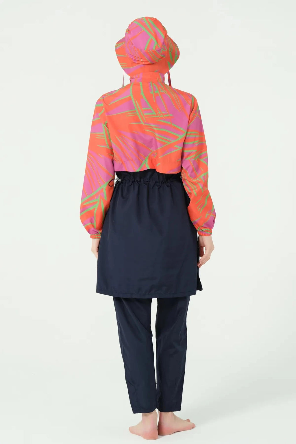 Woman in navy and orange burkini set with bucket hat, back view.