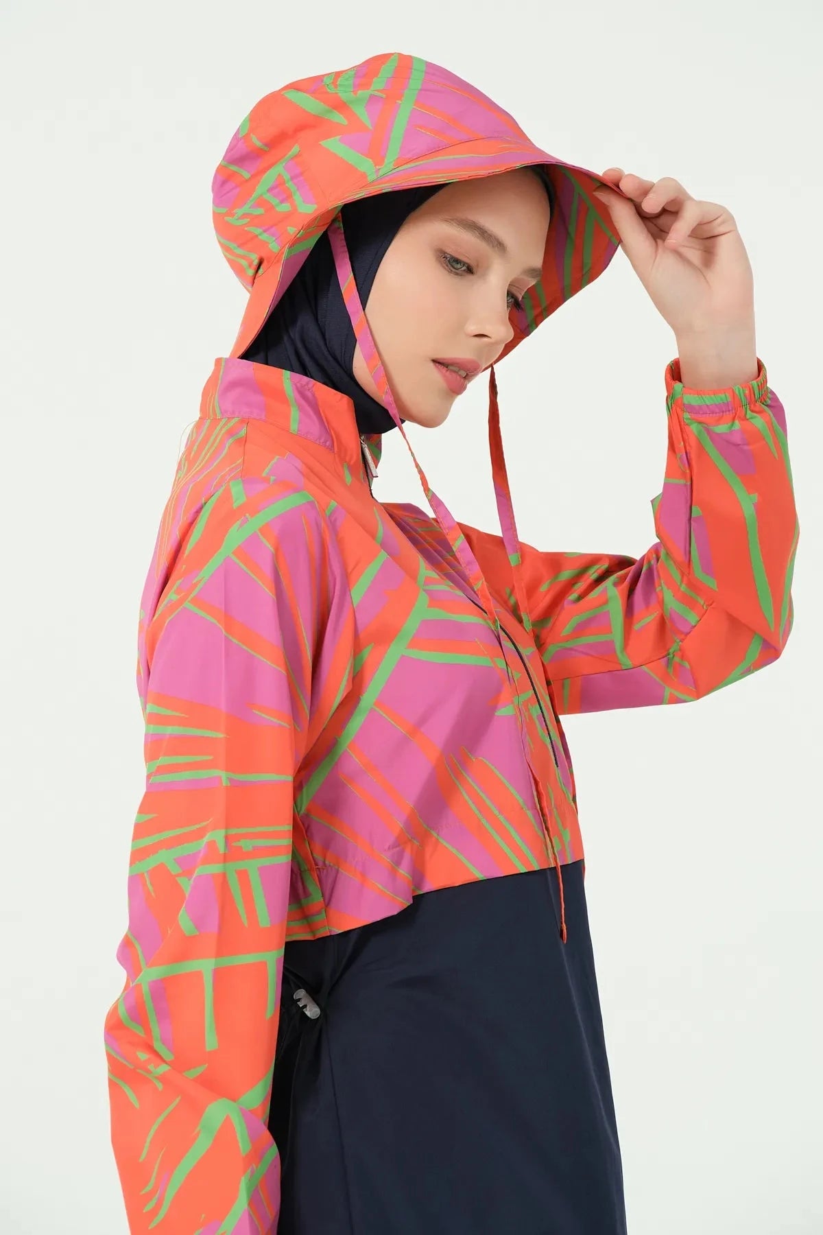Woman in navy and orange burkini set with bucket hat, side profile.