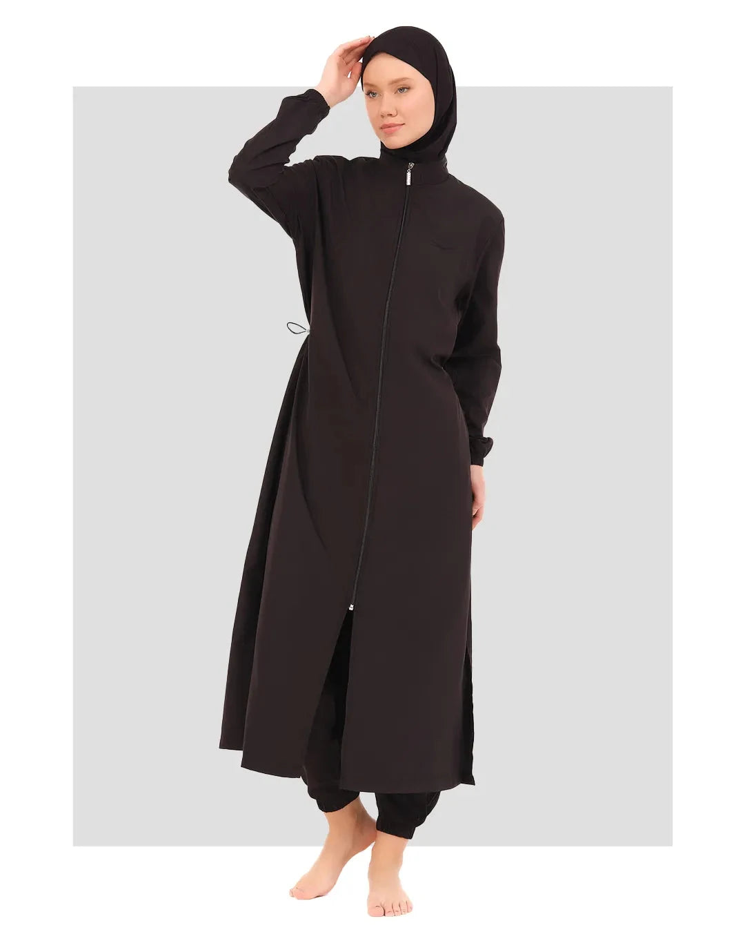 Woman in black full-length burkini with zipper and head covering.