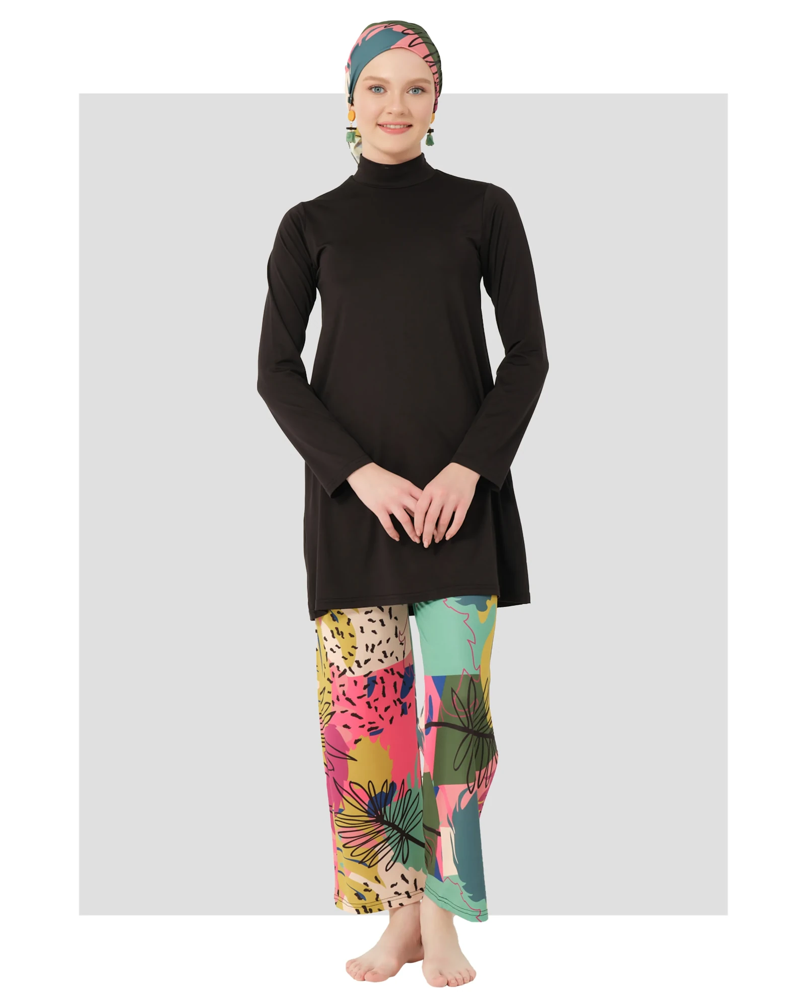 Woman in black burkini with colorful abstract print pants and matching head covering.