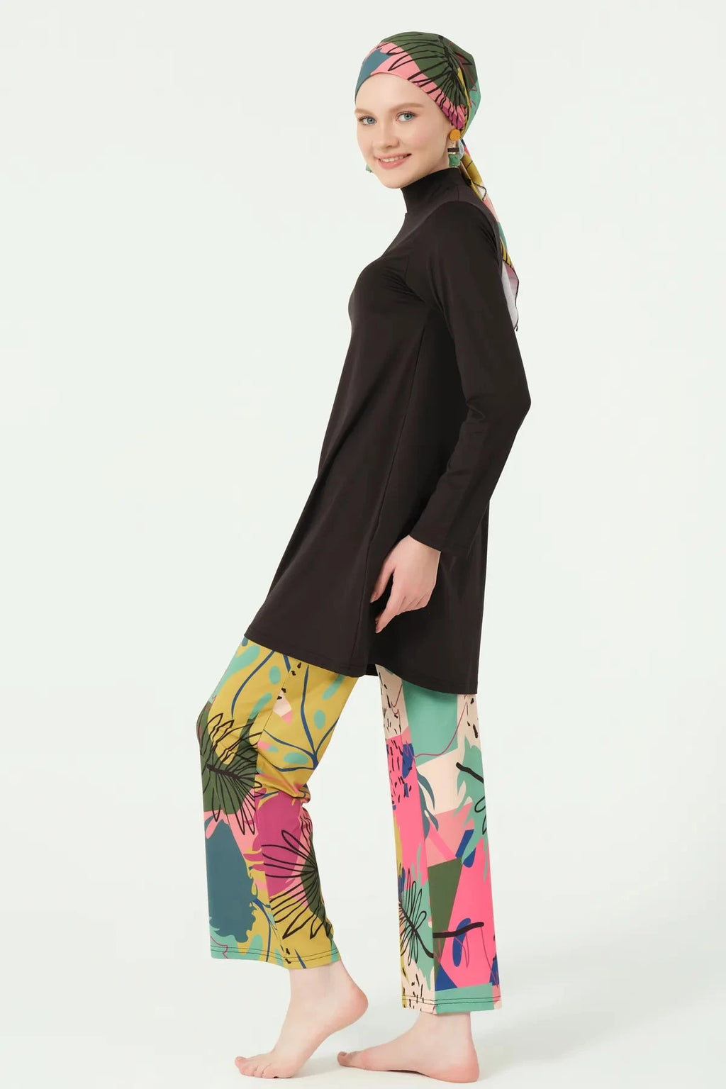 Side profile of woman in black burkini with colorful abstract print bottoms.