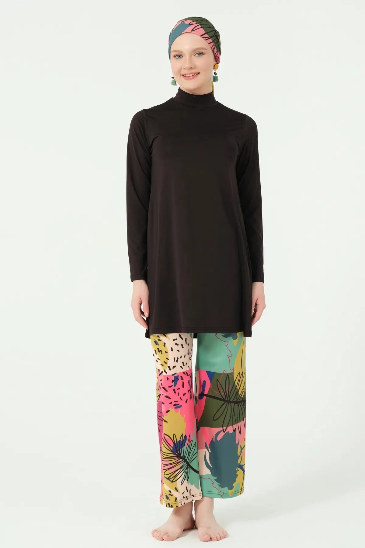 Full length front view of woman in black burkini and abstract print pants.