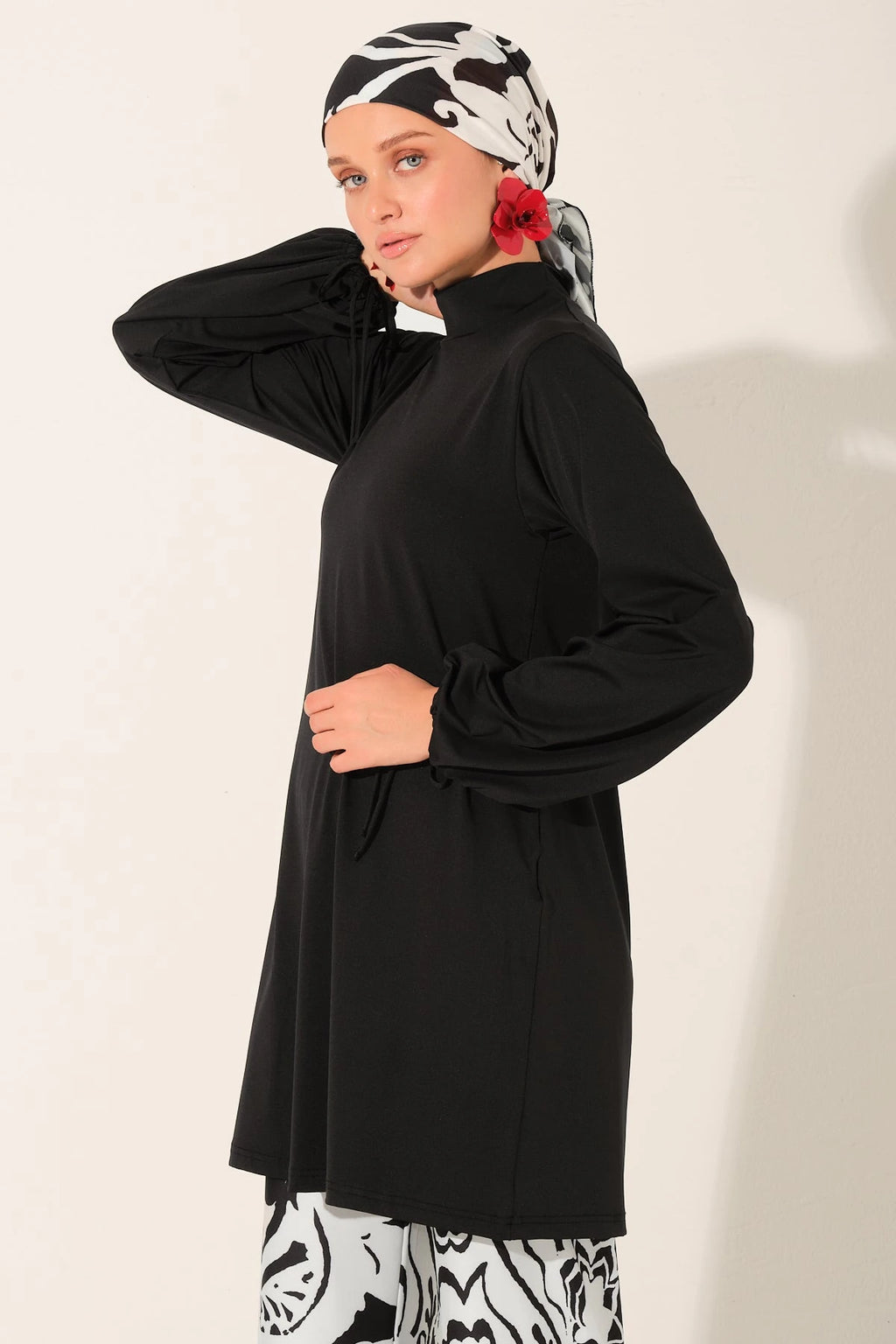 Close-up of woman in black swim top and patterned head scarf, side profile.
