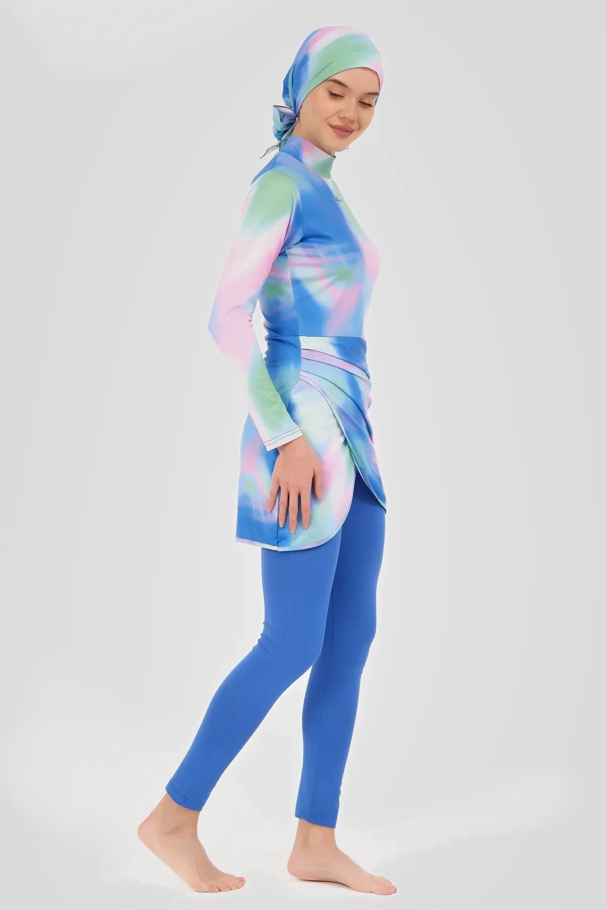 Woman in pastel tie-dye burkini set side view, walking confidently.