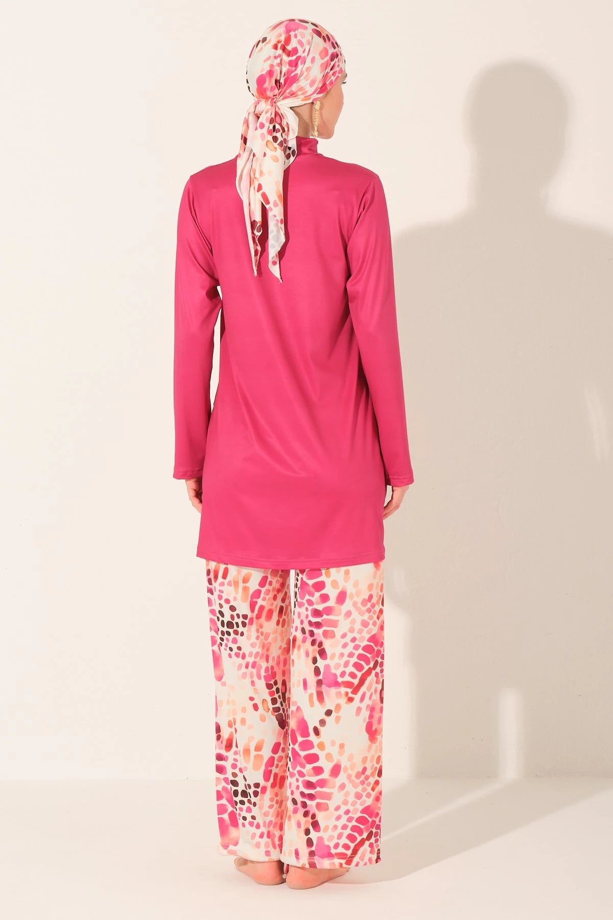 Back view of fuchsia burkini top and patterned swim pants with headscarf.