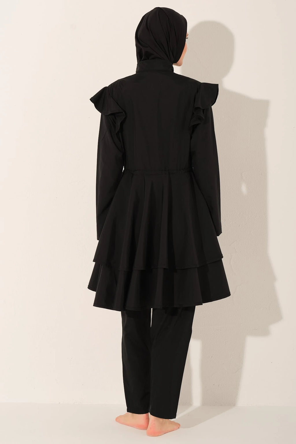 Black ruffle burkini set back view on model.