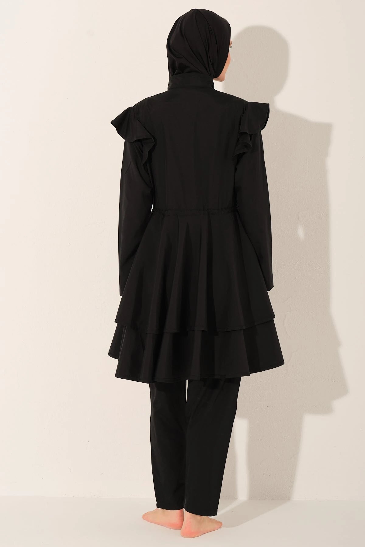 Black ruffle burkini set back view on model.