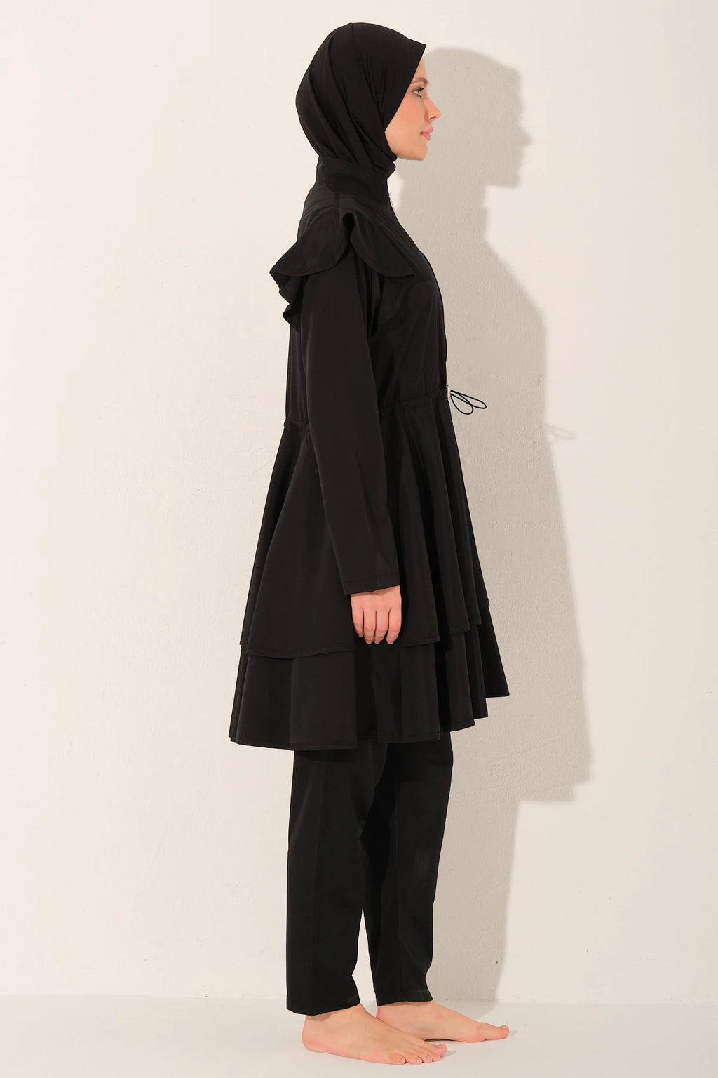 Black ruffle burkini set side view on model.