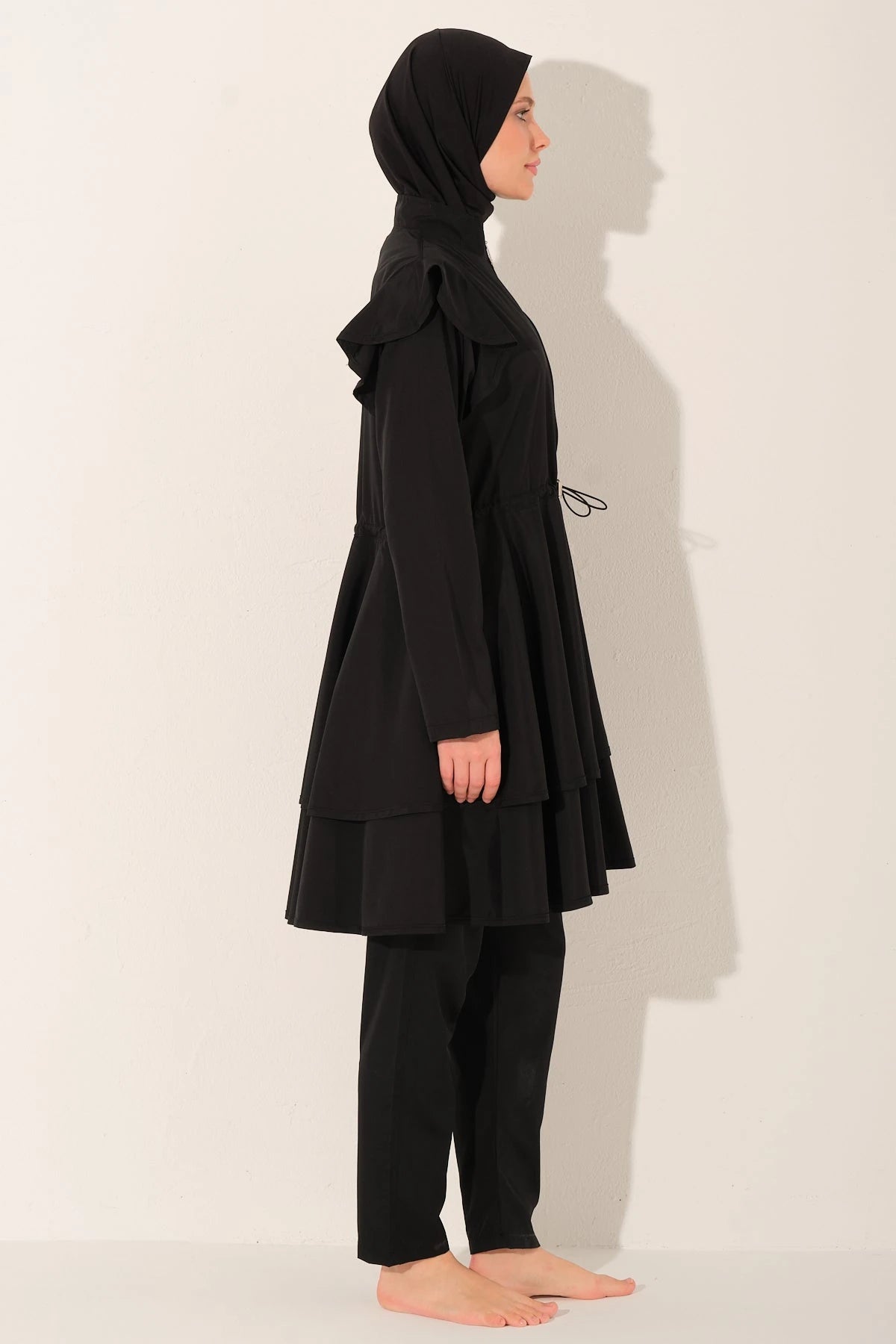 Black ruffle burkini set side view on model.