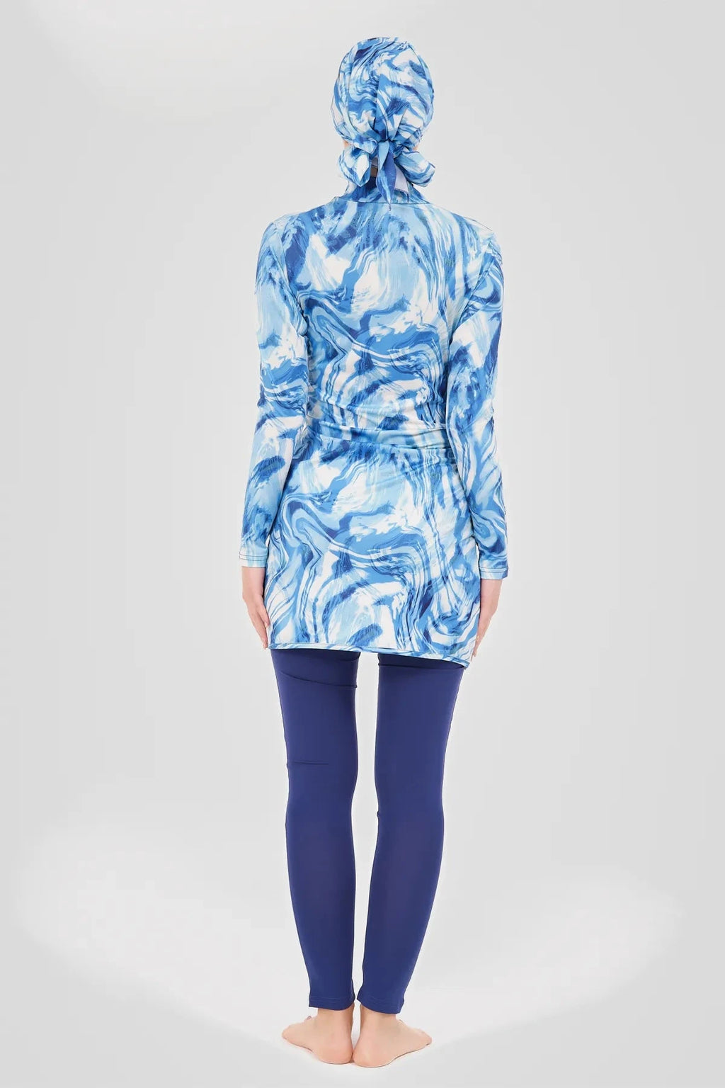 Model in blue wave print burkini top and swim pants, back view.