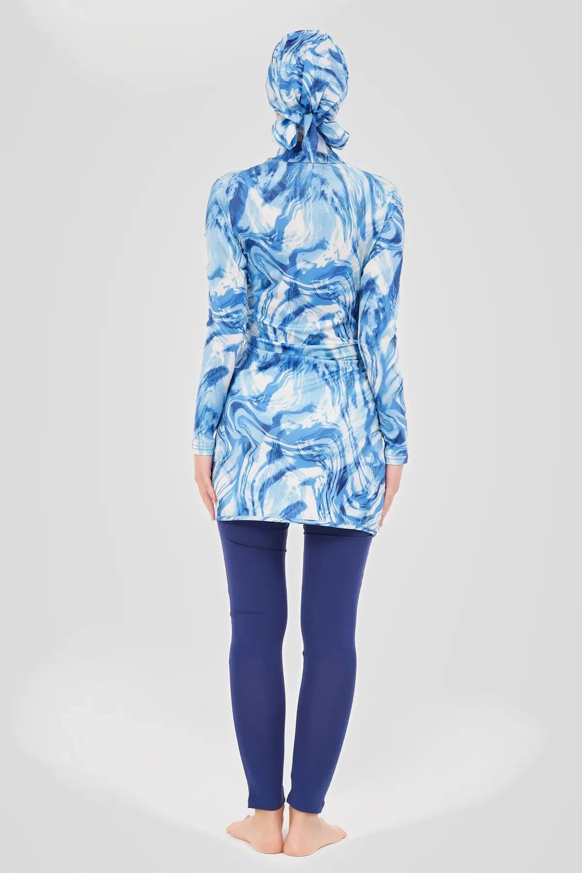 Model in blue wave print burkini top and swim pants, back view.