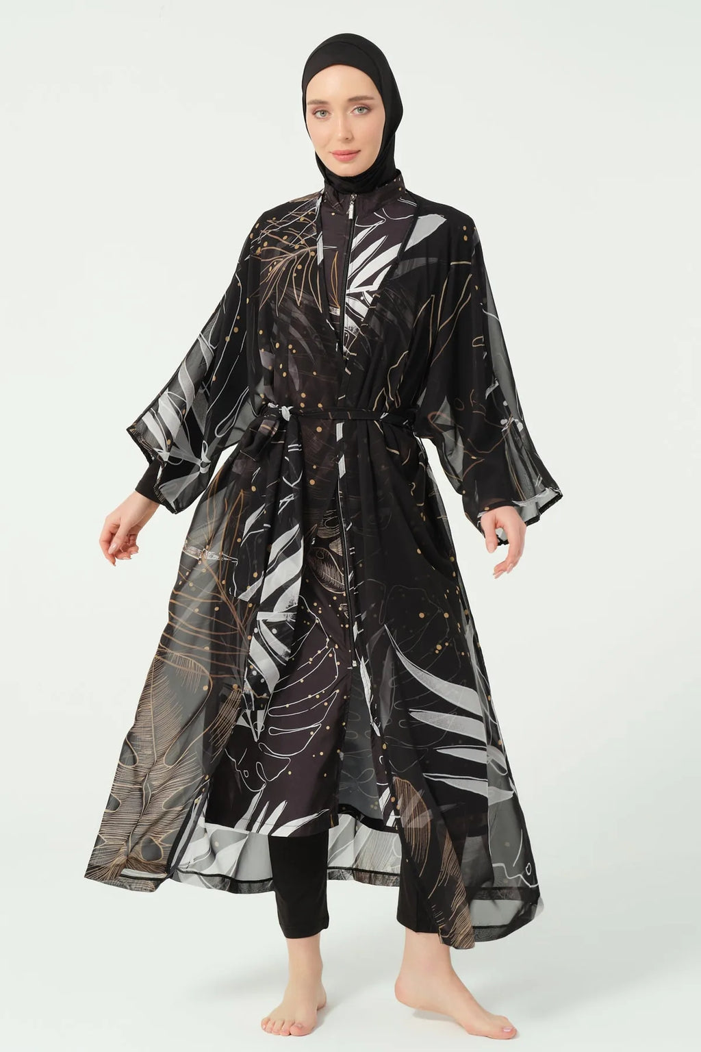 Model in black burkini with gold and white leaf print kimono, arms open.