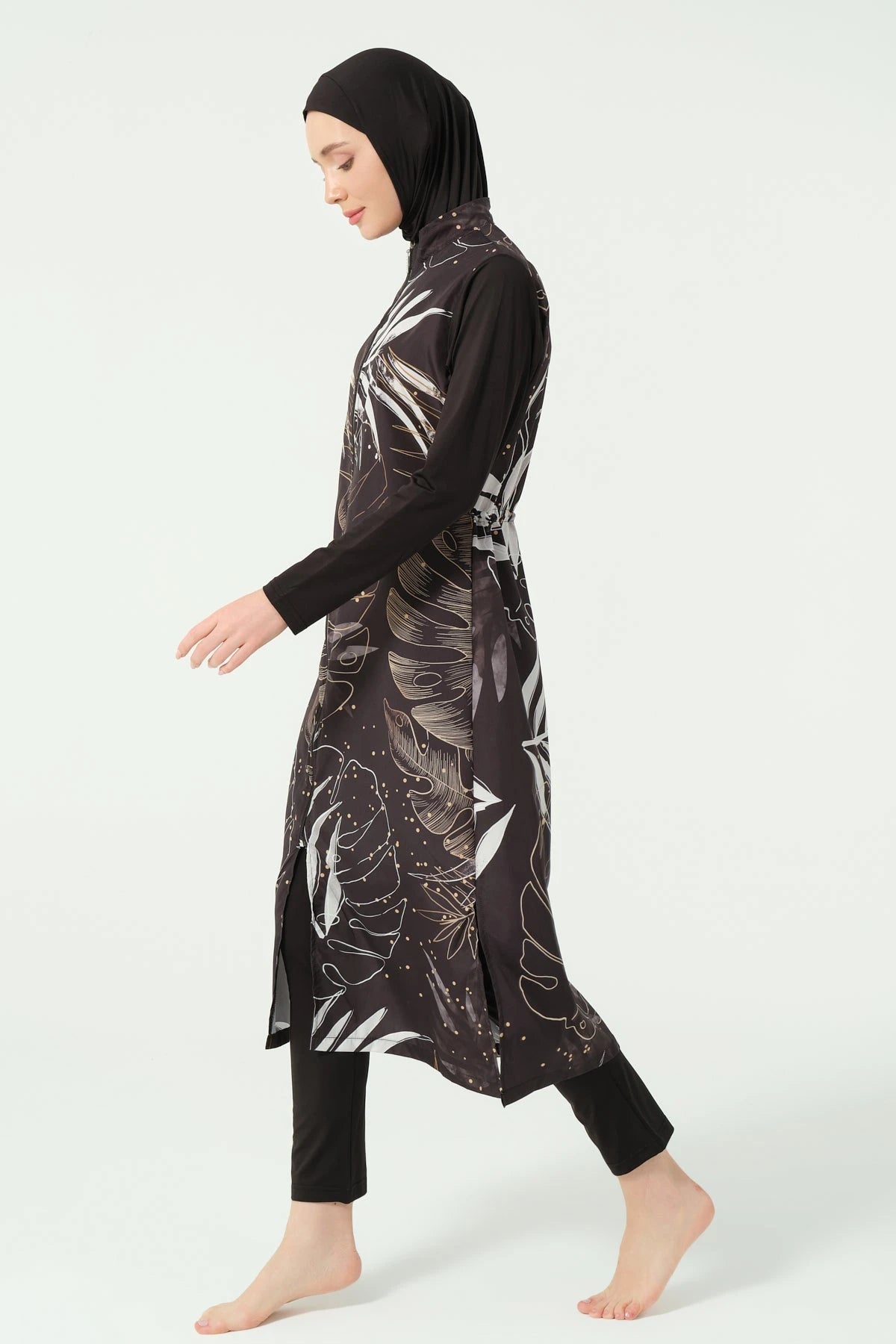 Side view of black burkini top with leaf print and black swim pants.