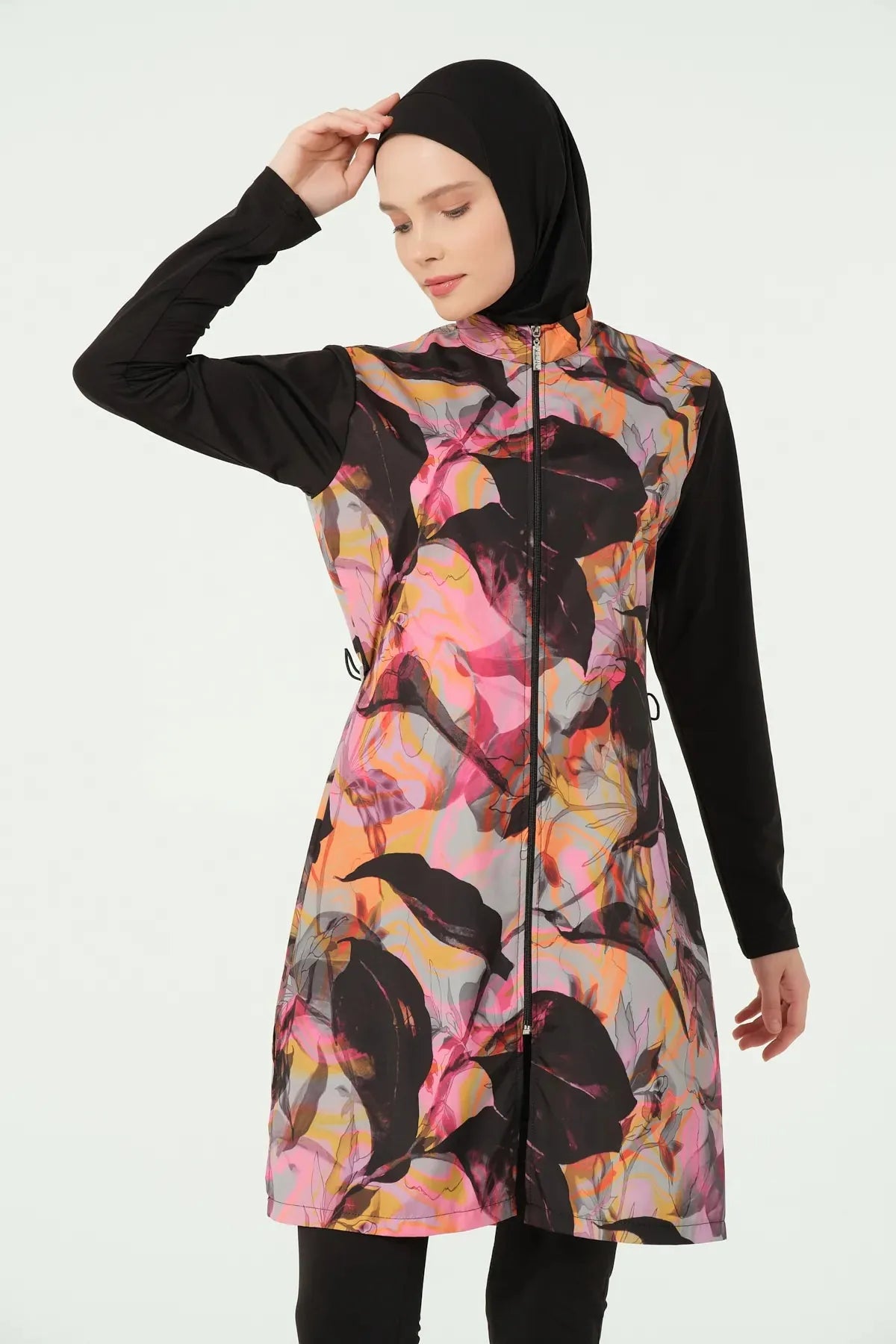 Woman in black abstract print burkini, front view, adjusting hijab.