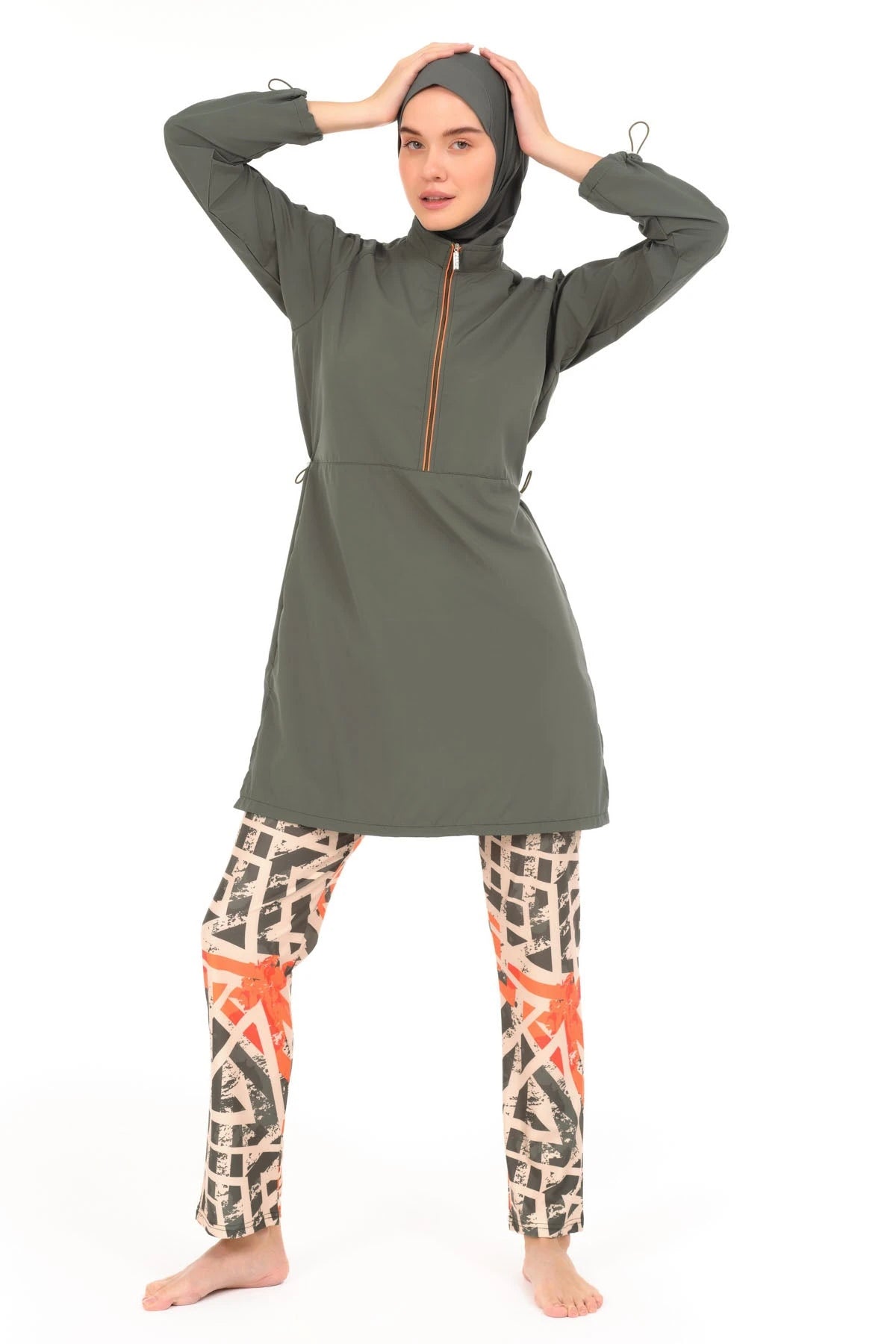 Woman in modern burkini with geometric print, hands on head.