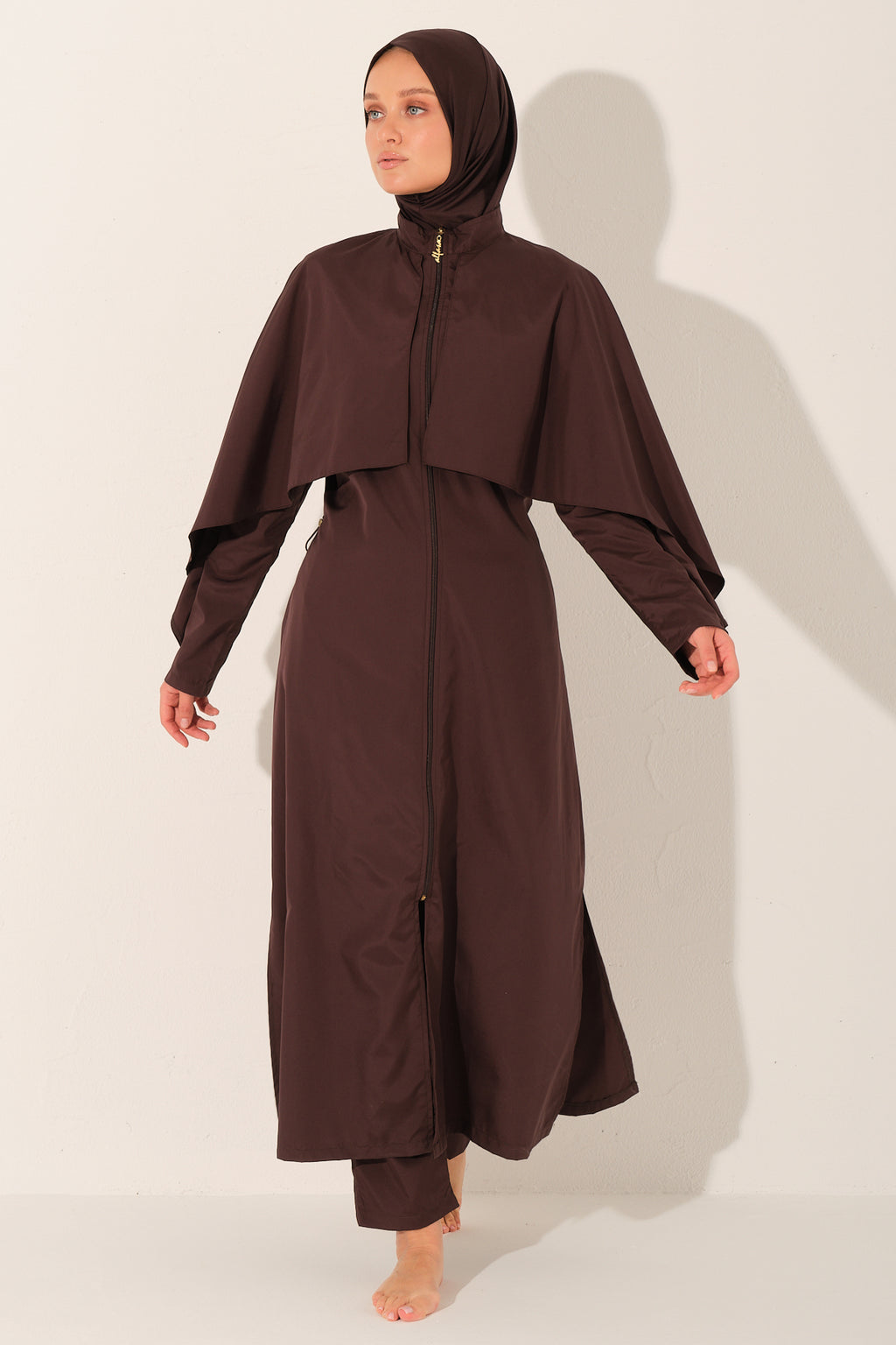 Woman wearing a brown outfit modest swimwear with a hijab on a white background
