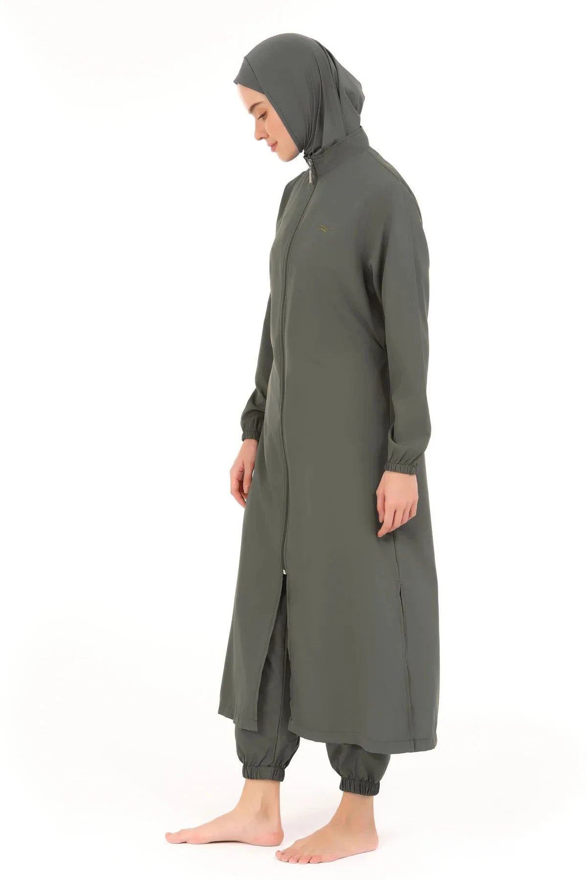 Model in olive green full-length burkini with integrated hijab cap profile view.