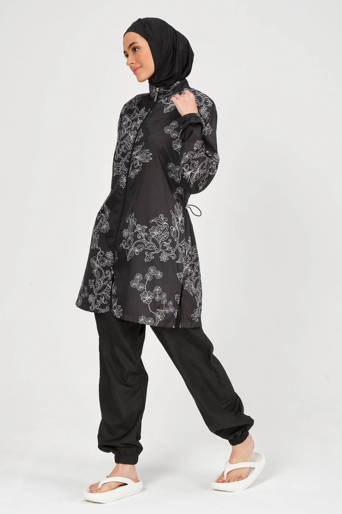 Black burkini set with white floral embroidery, side view.