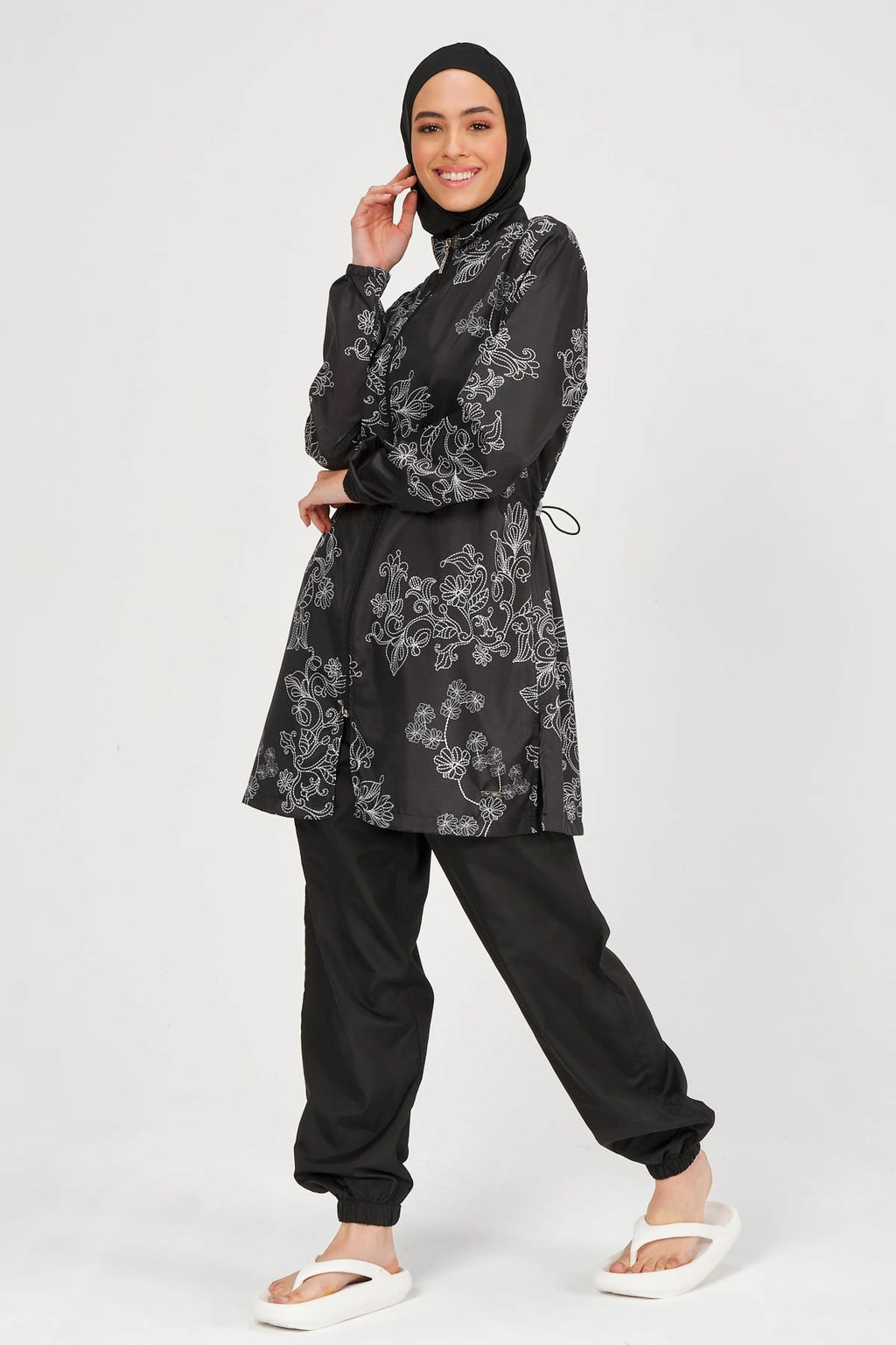 Black burkini set with white floral embroidery, model posing.
