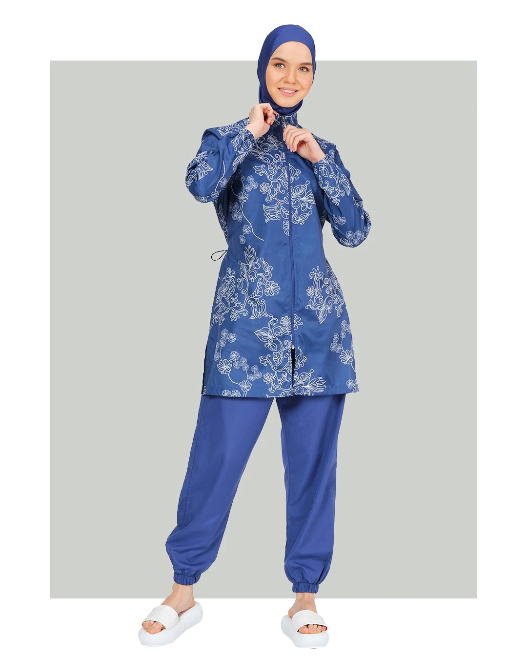 Blue burkini set with floral embroidery, front view, on grey background.