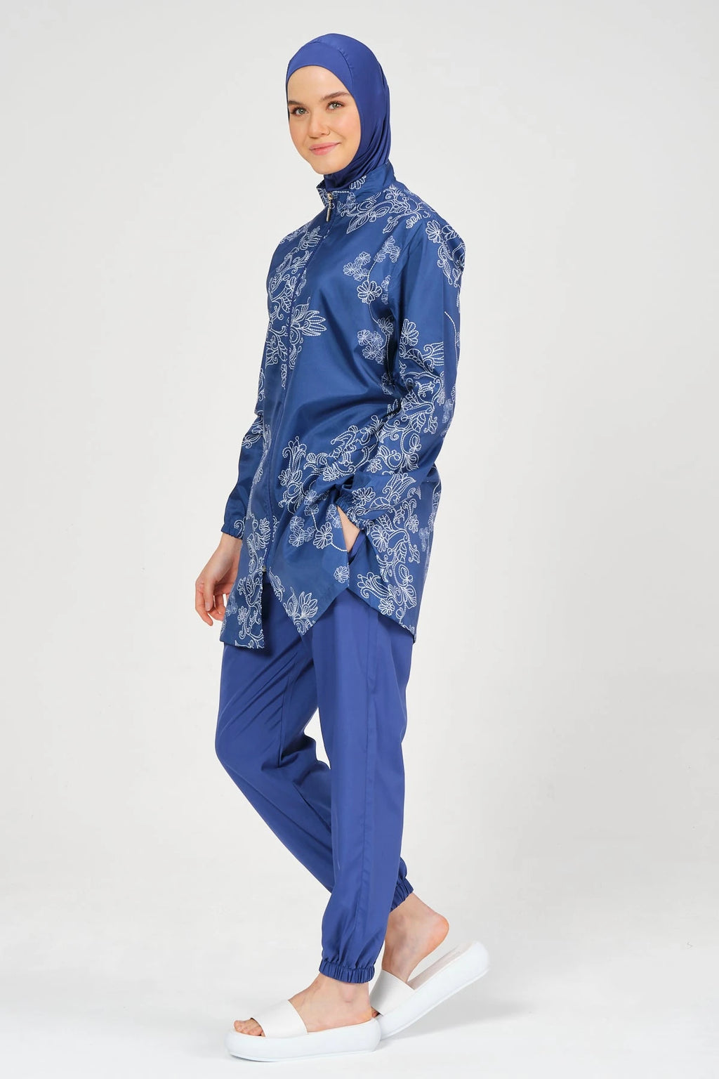 Blue burkini set with floral embroidery, side view, on white background.