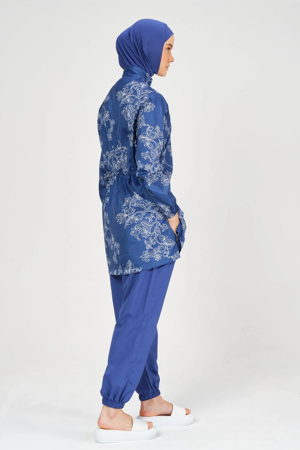 Blue burkini set with floral embroidery, side detail, on white background.