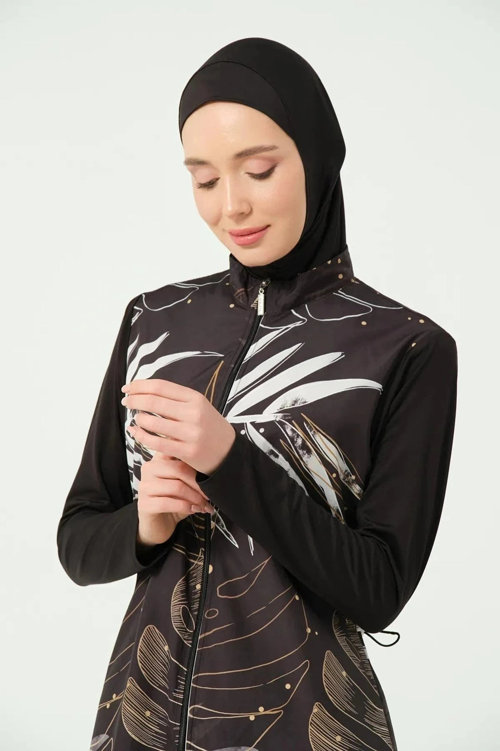 Close-up of woman's hands adjusting black burkini with leaf print.