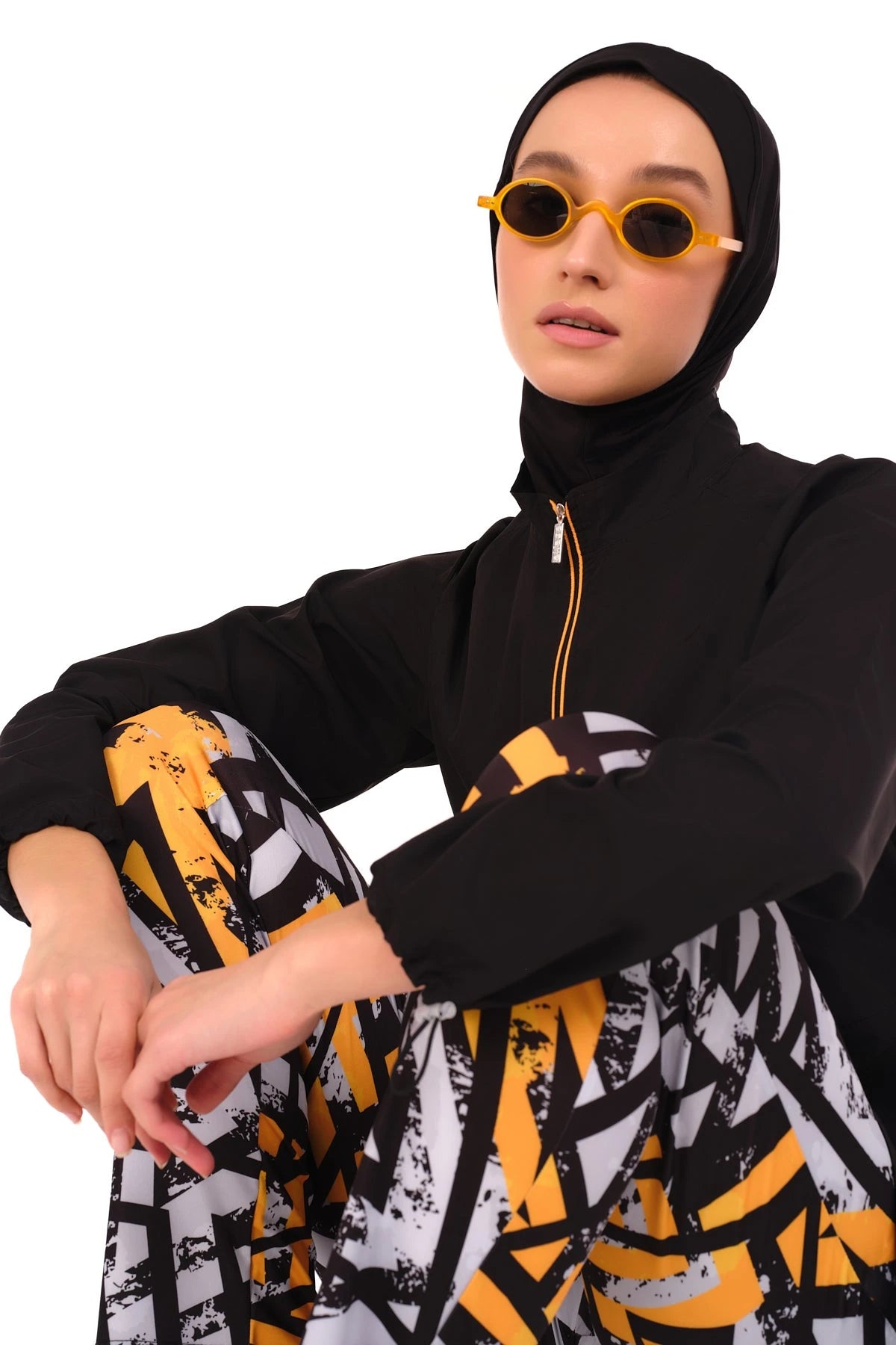 Close-up of burkini top and geometric pants with yellow sunglasses.