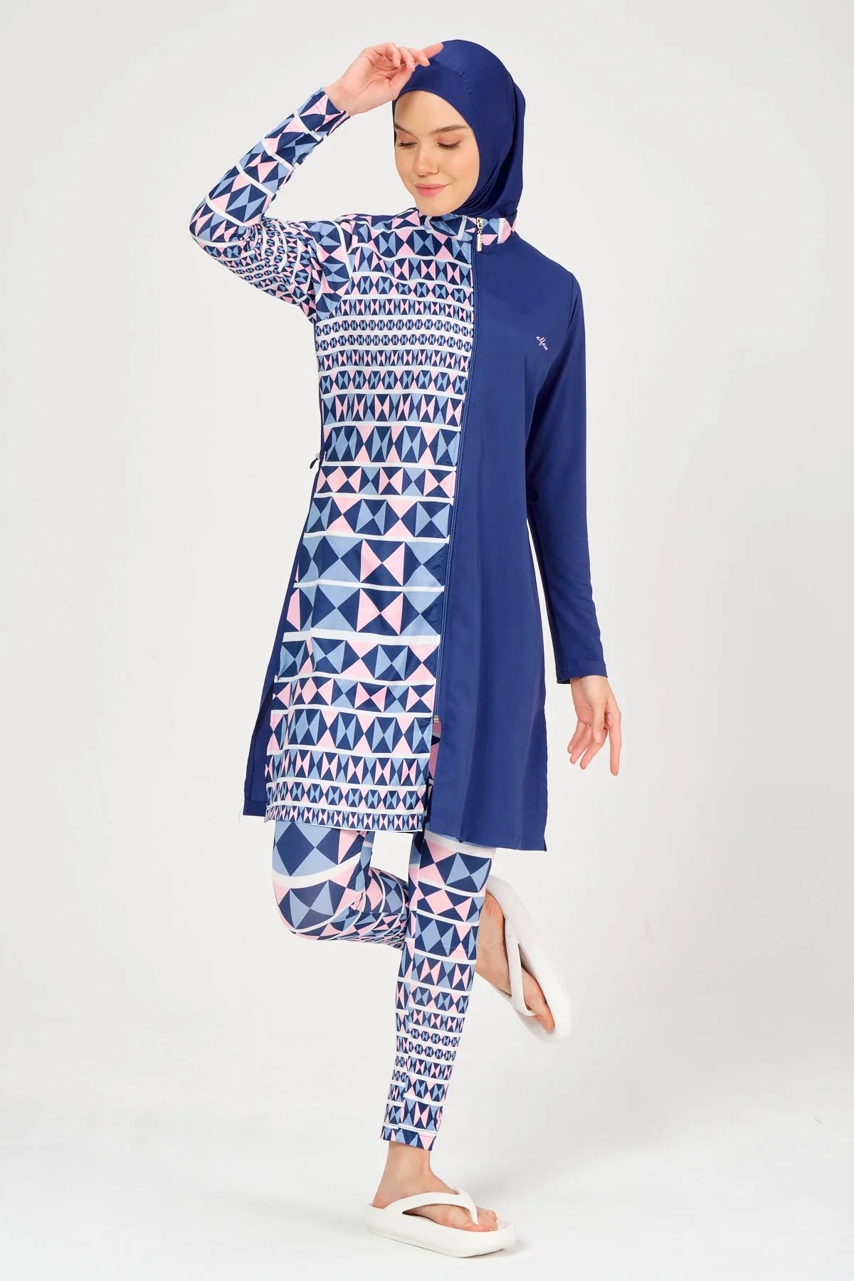 Model in blue and geometric burkini posing with leg raised.