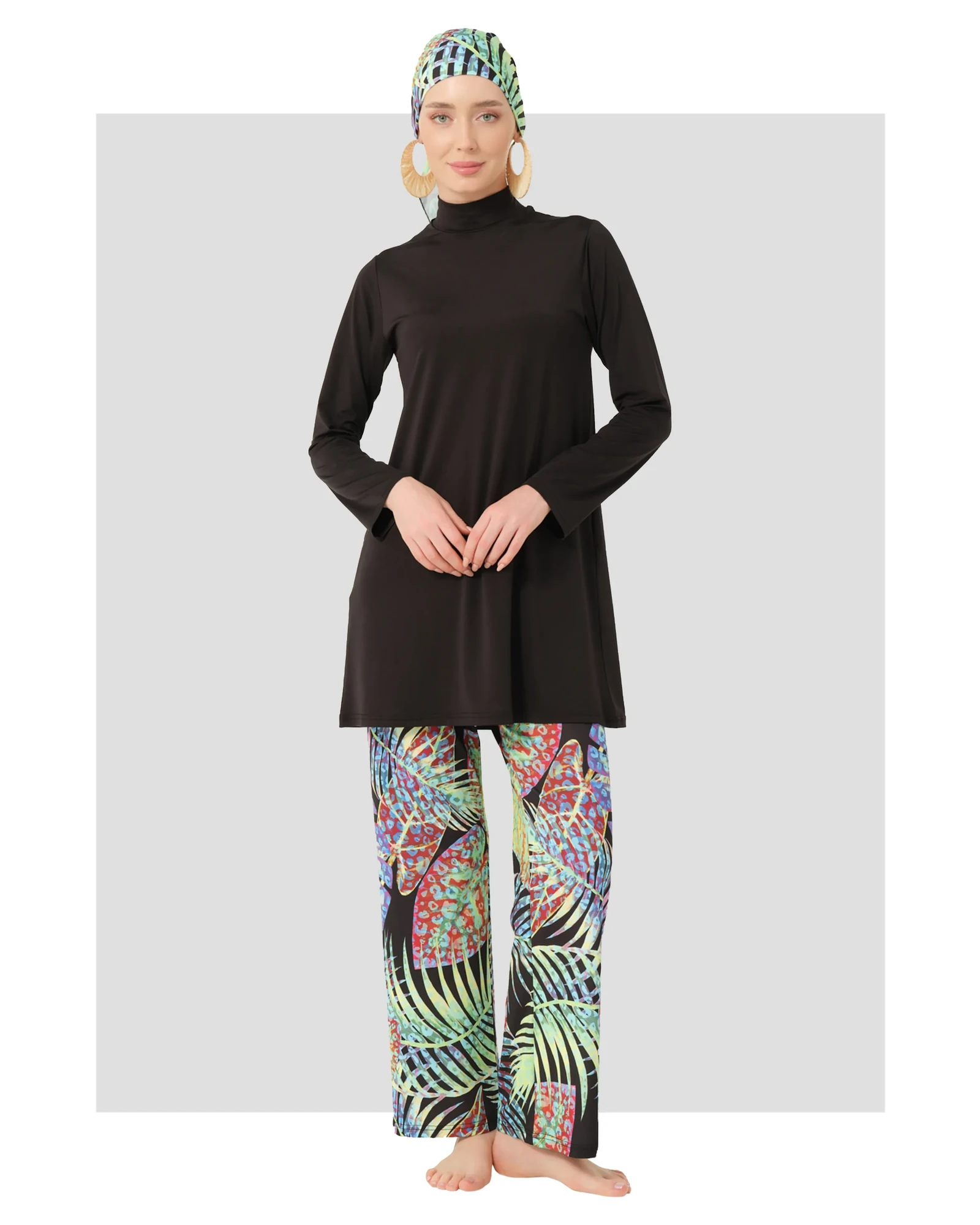 Model in black burkini with tropical print pants and matching cap.