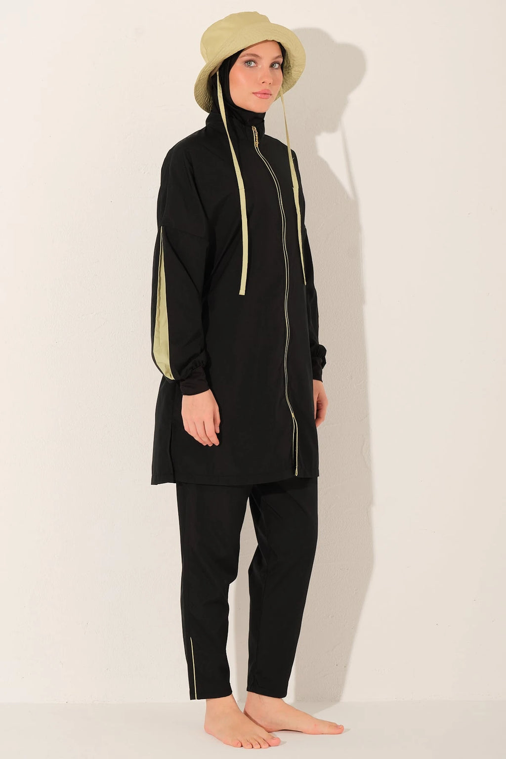 Black burkini set with yellow drawstrings, light bucket hat, side angle.