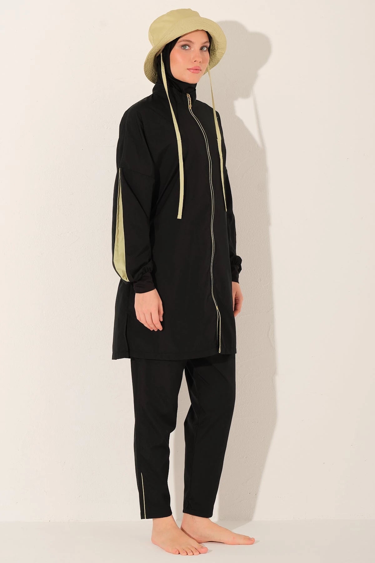 Black burkini set with yellow drawstrings, light bucket hat, side angle.