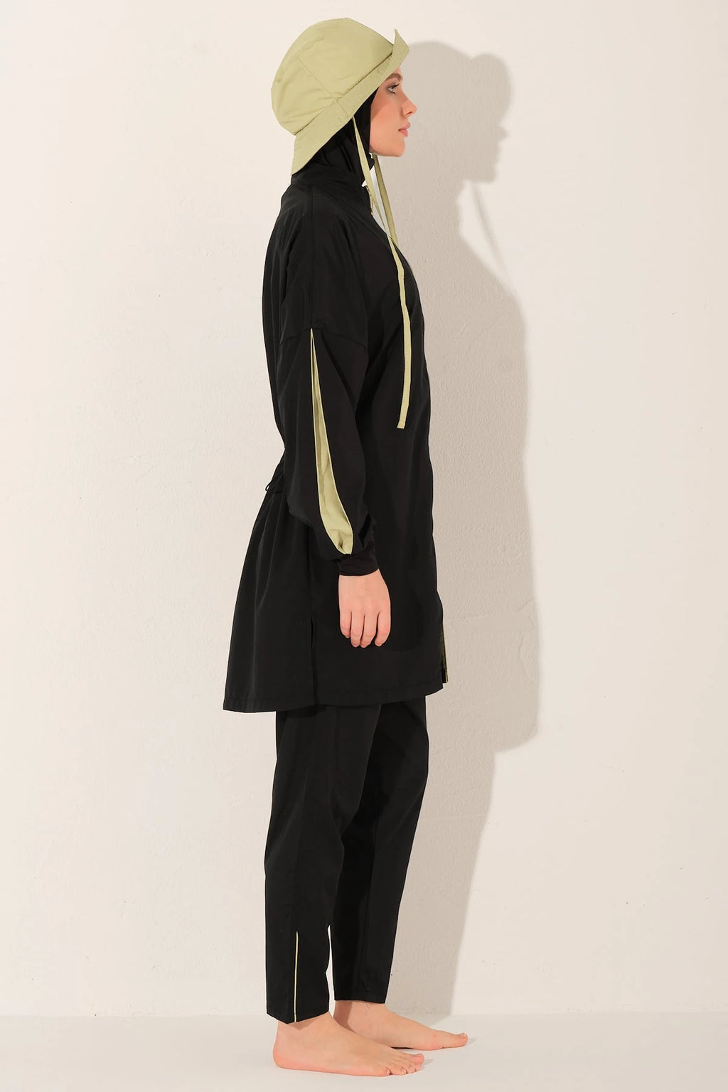Black burkini set with yellow drawstrings and light bucket hat, side view.