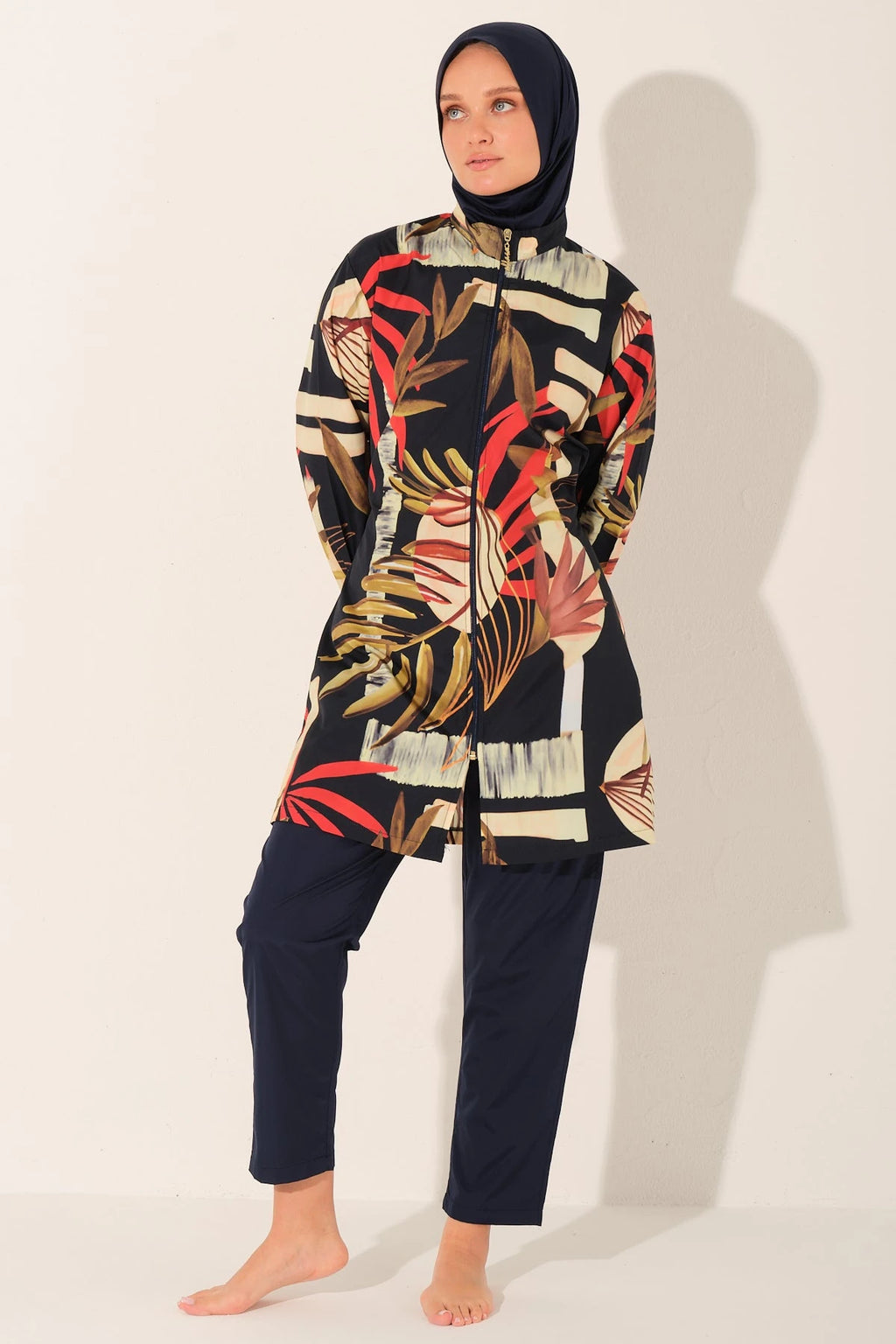 Front view of model in tropical print burkini set, hands behind back.