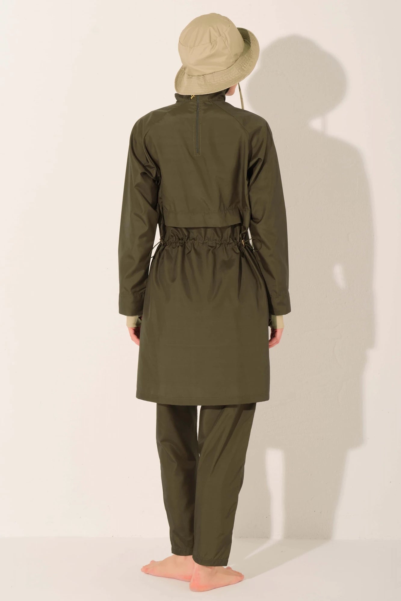 Woman in olive trail burkini and beige hat, back view.