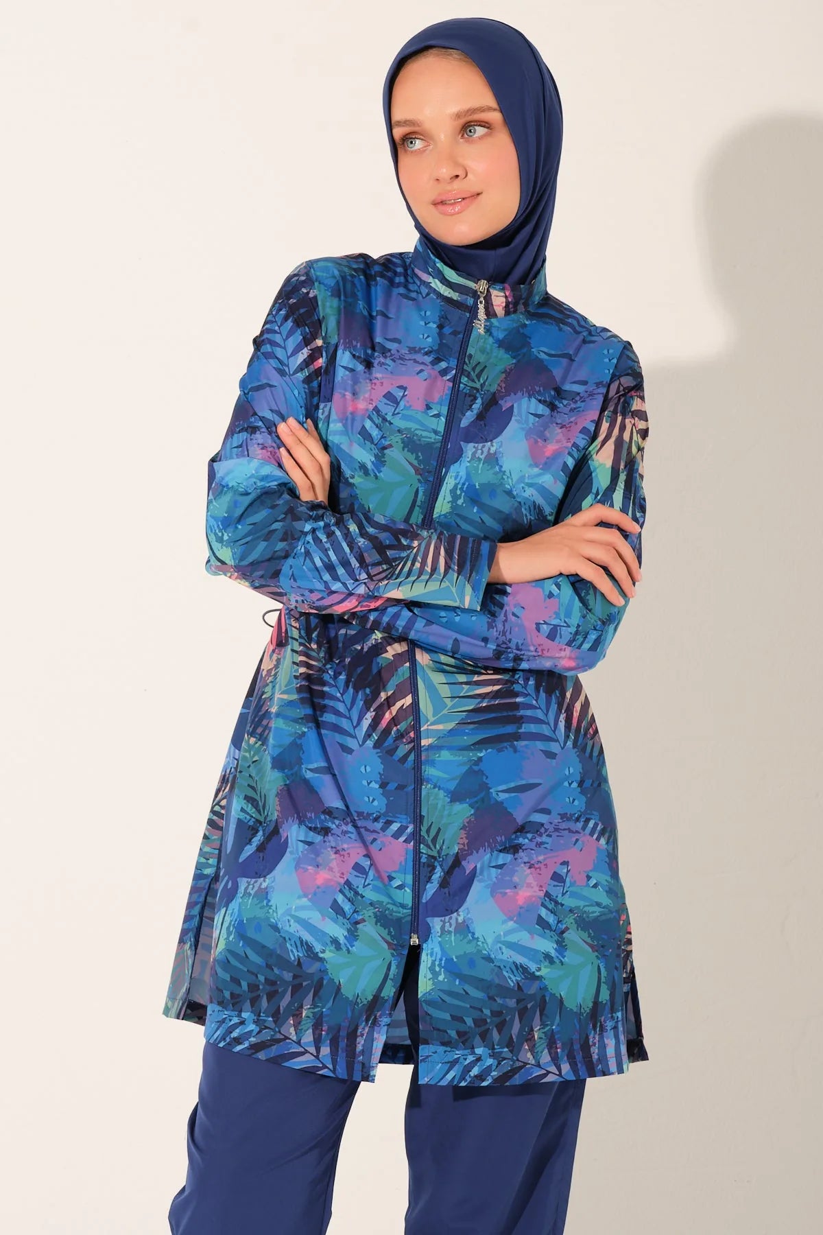 Model in blue tropical burkini set, arms crossed, showing drawstring waist.