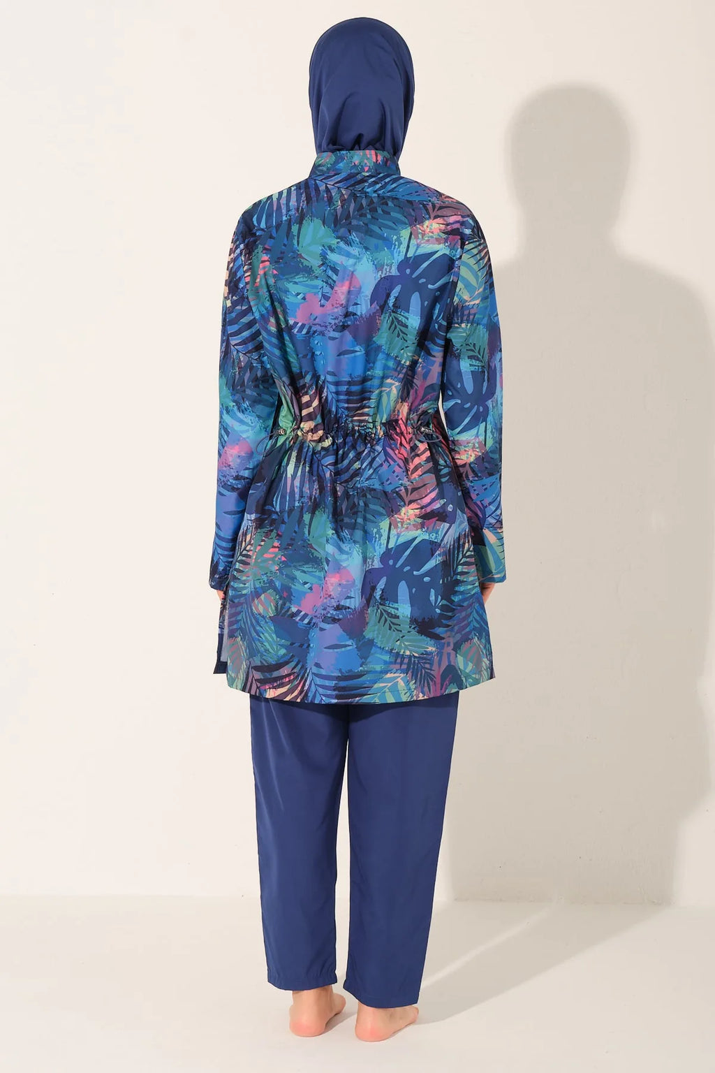 Model wearing blue tropical print burkini set, back view, showing waist detail.