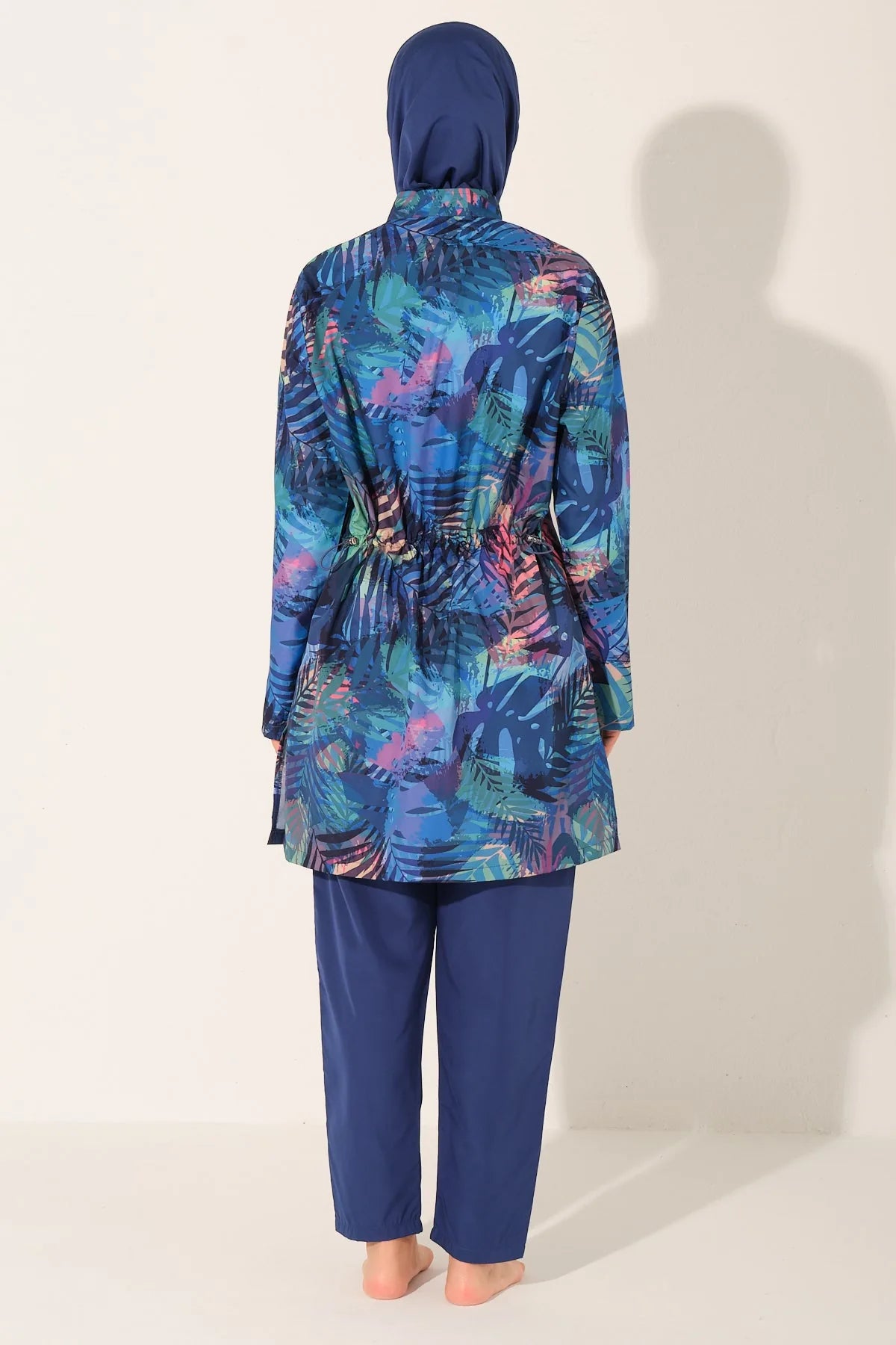 Model wearing blue tropical print burkini set, back view, showing waist detail.