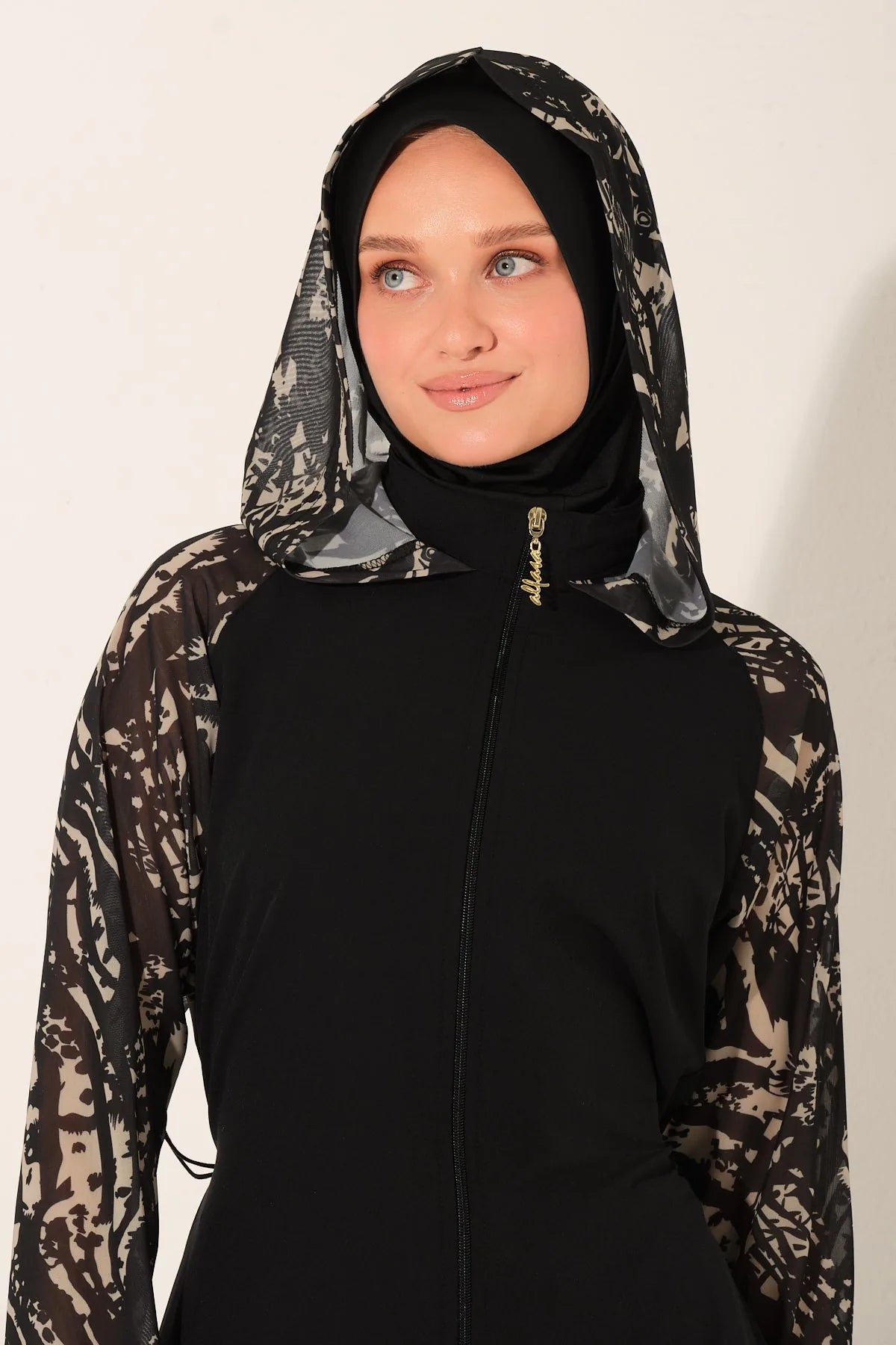 Close-up of black burkini hood with patterned fabric and gold zipper.