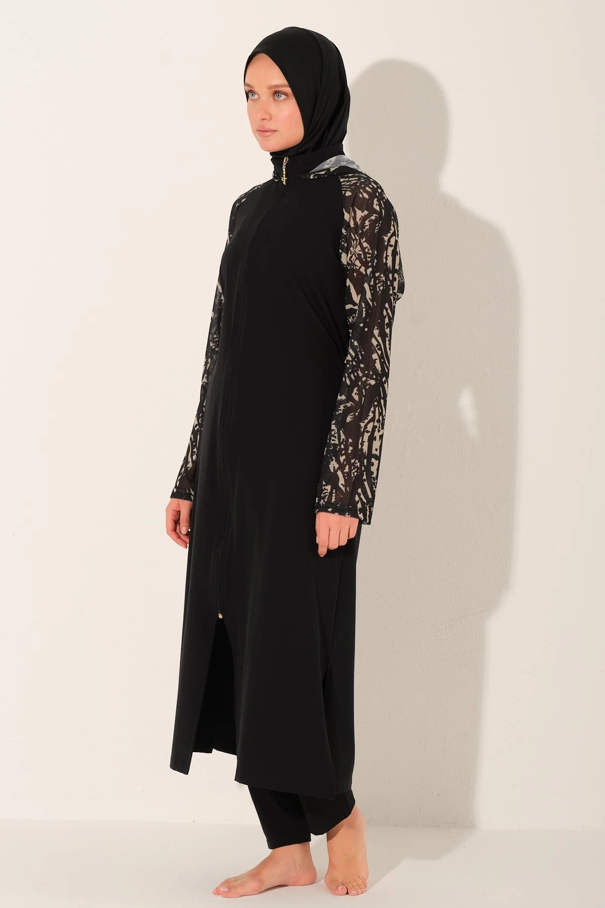 Black burkini set with patterned sleeves, side view on light background.