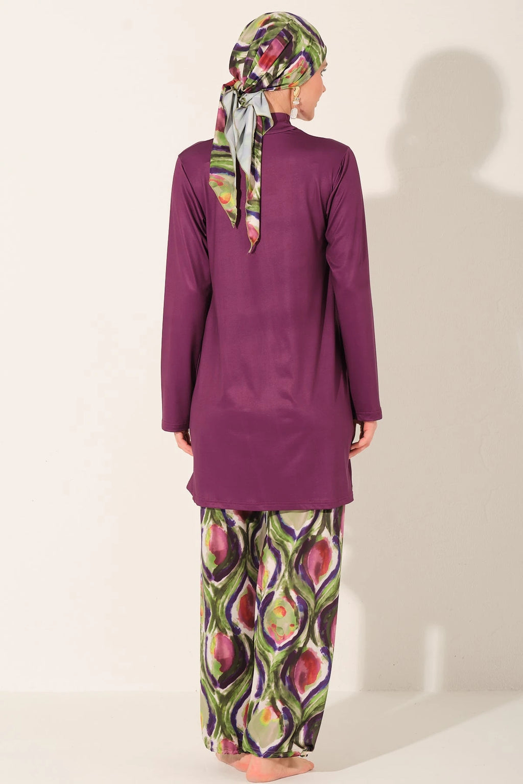 Back view of plum burkini set with abstract peacock print pants and headscarf.